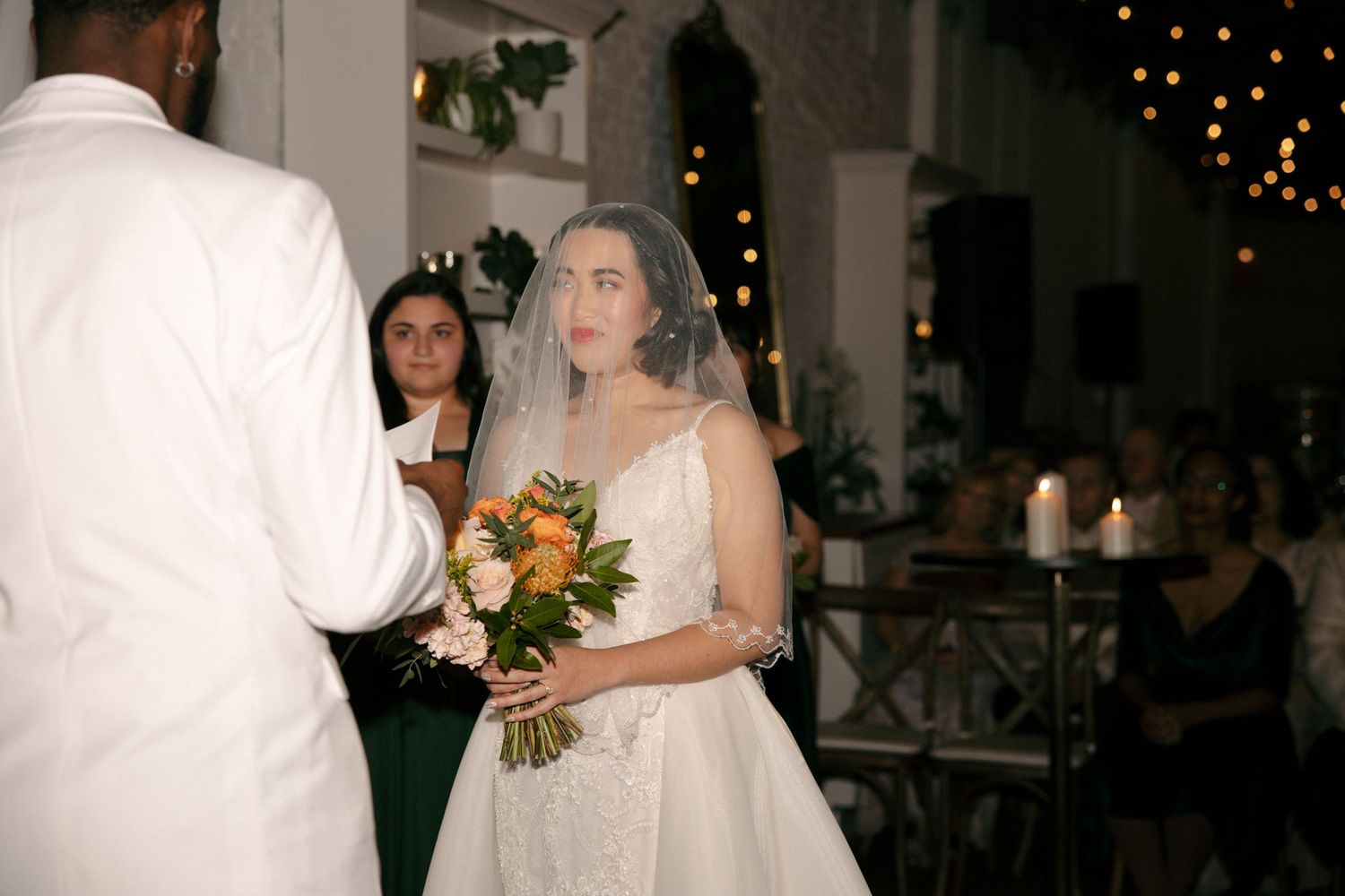 Wedding reception scene with string lights and elegant white decorations.