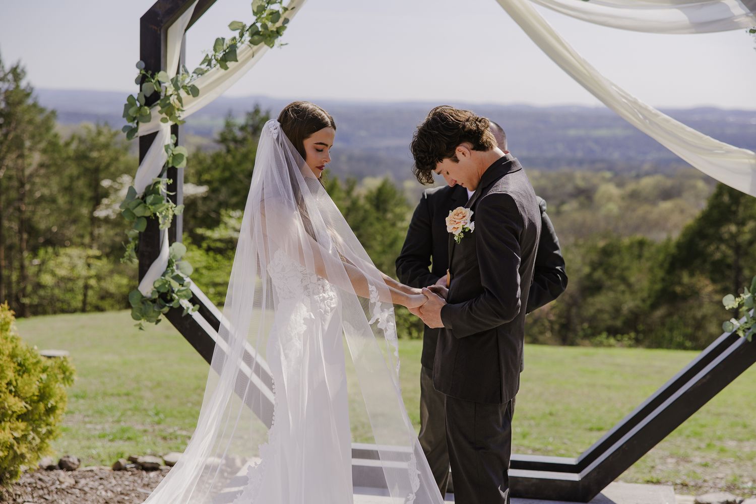 Wedding ceremony setup with flowing white fabric against mountain backdrop.