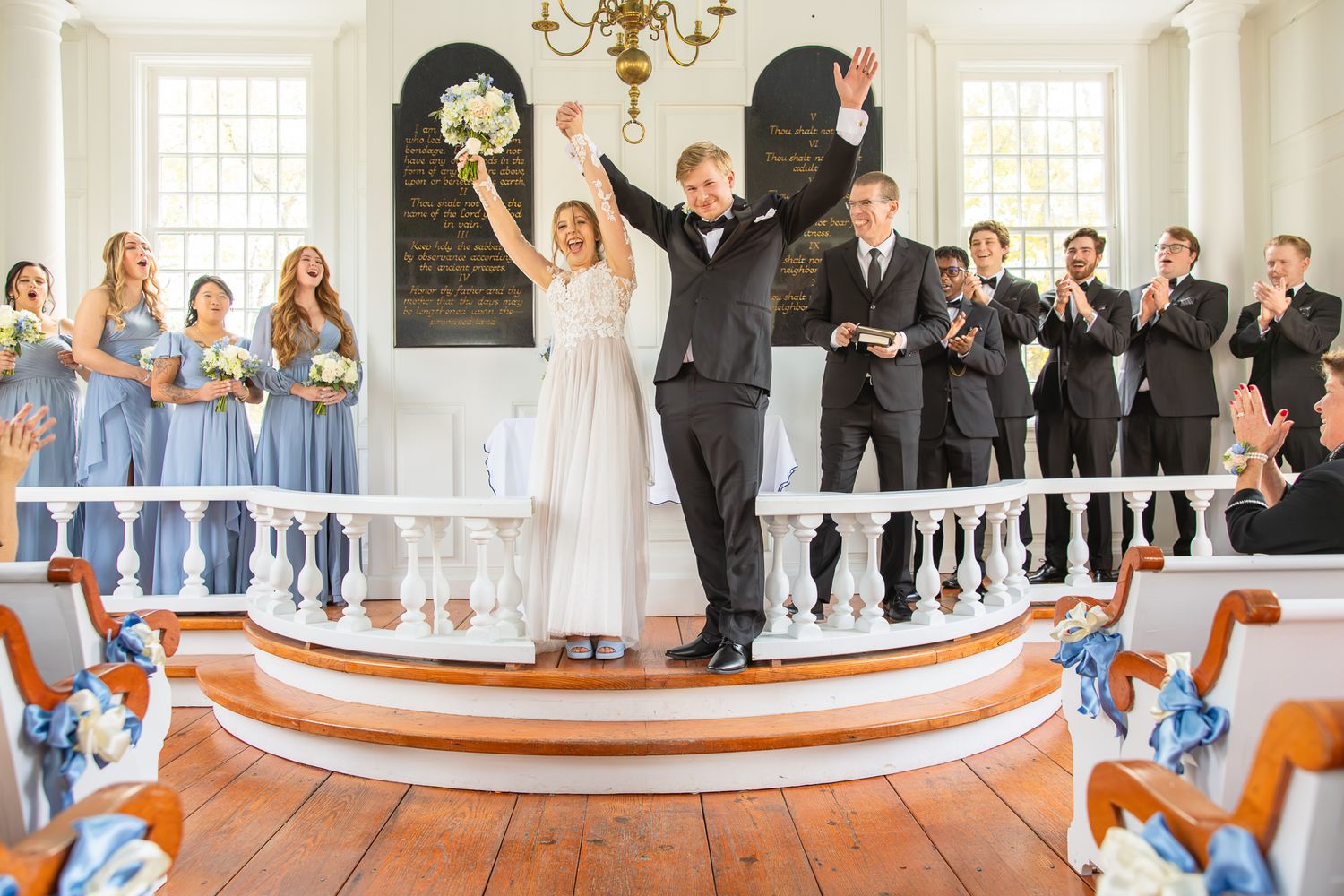 Wide angle view of church wedding ceremony with guests and blue-dressed wedding party.