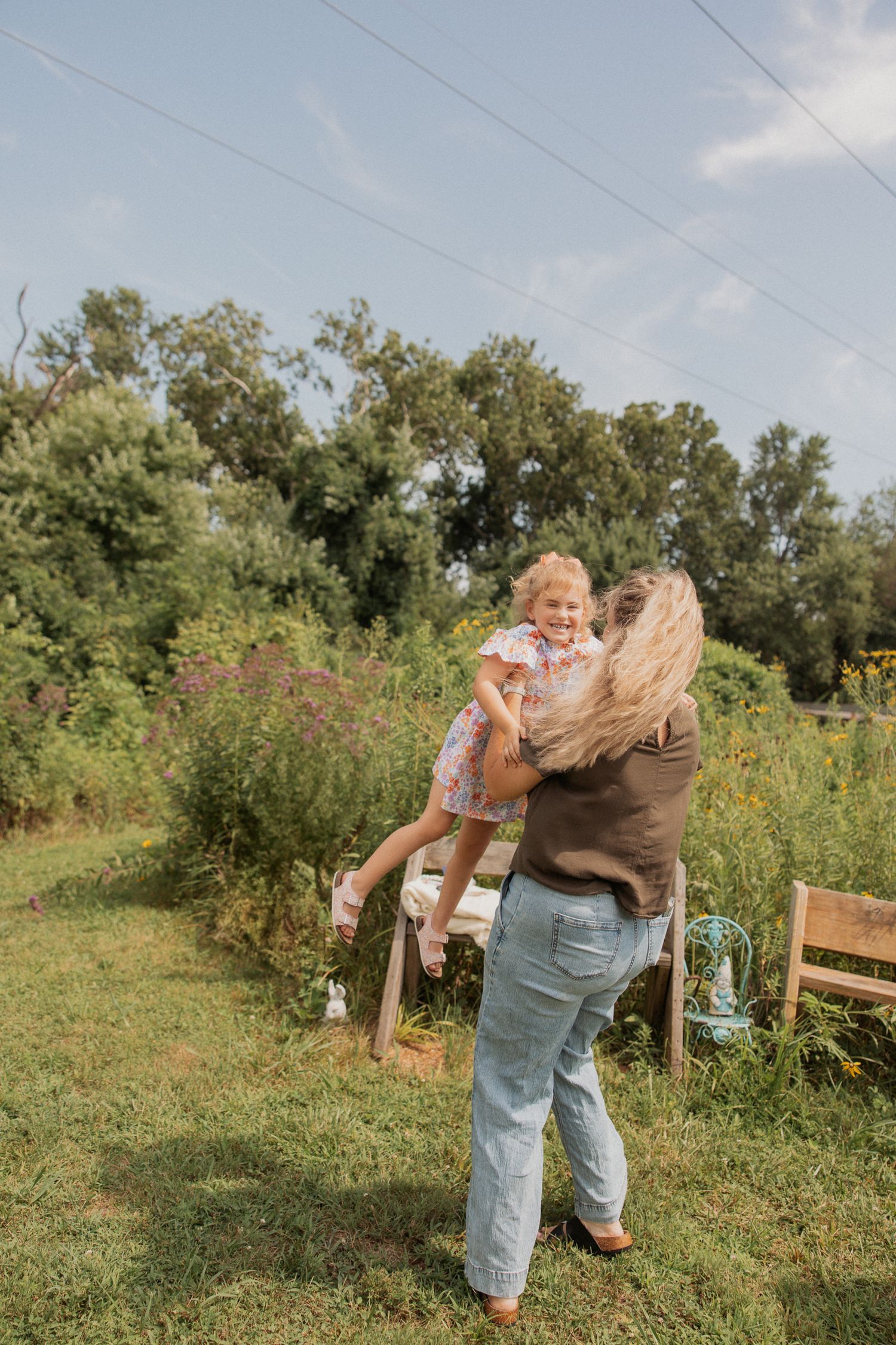 Candid moments of joy captured in a lush garden setting with wooden bench.