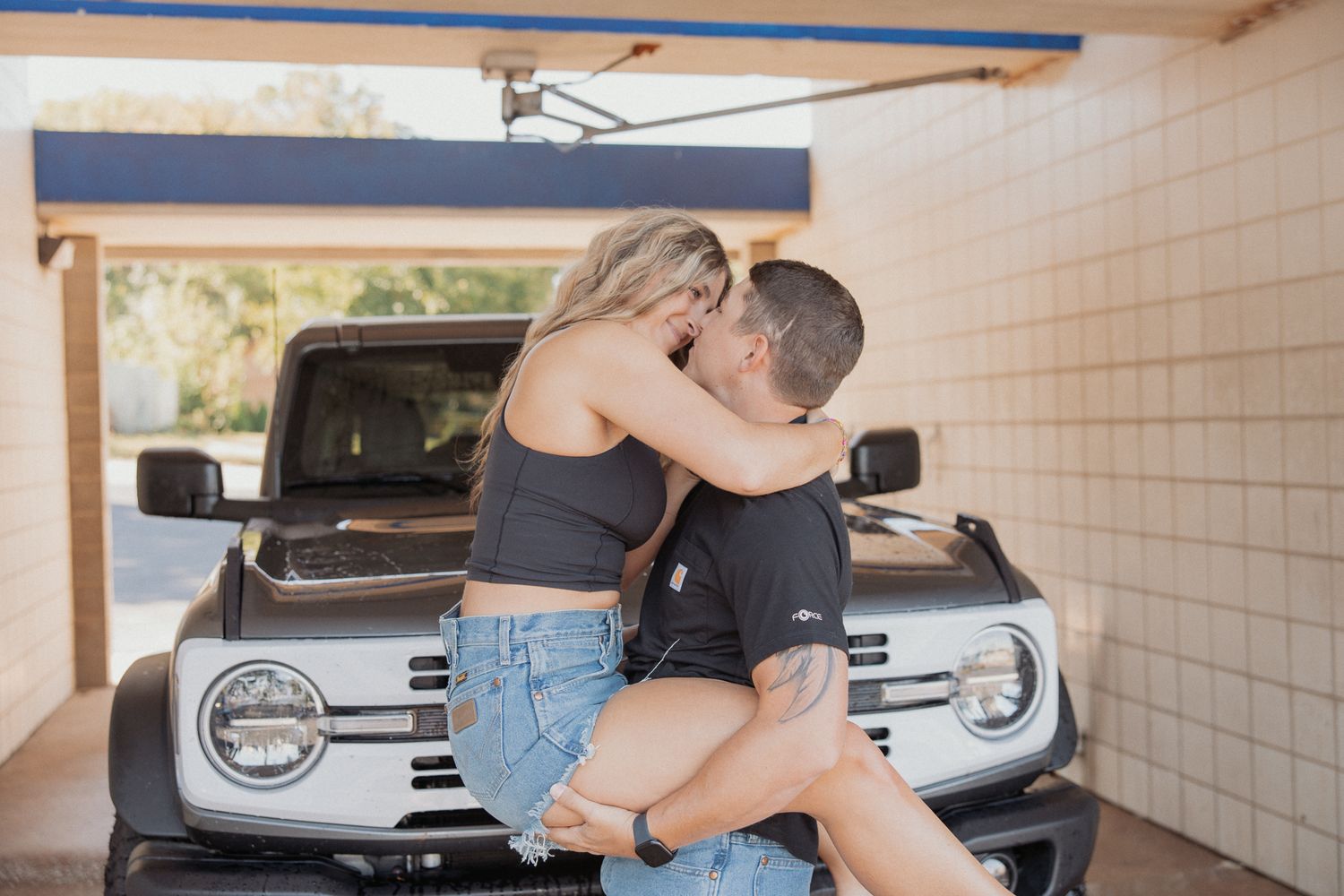 Romantic scene in a parking garage with couple and white vehicle in background.