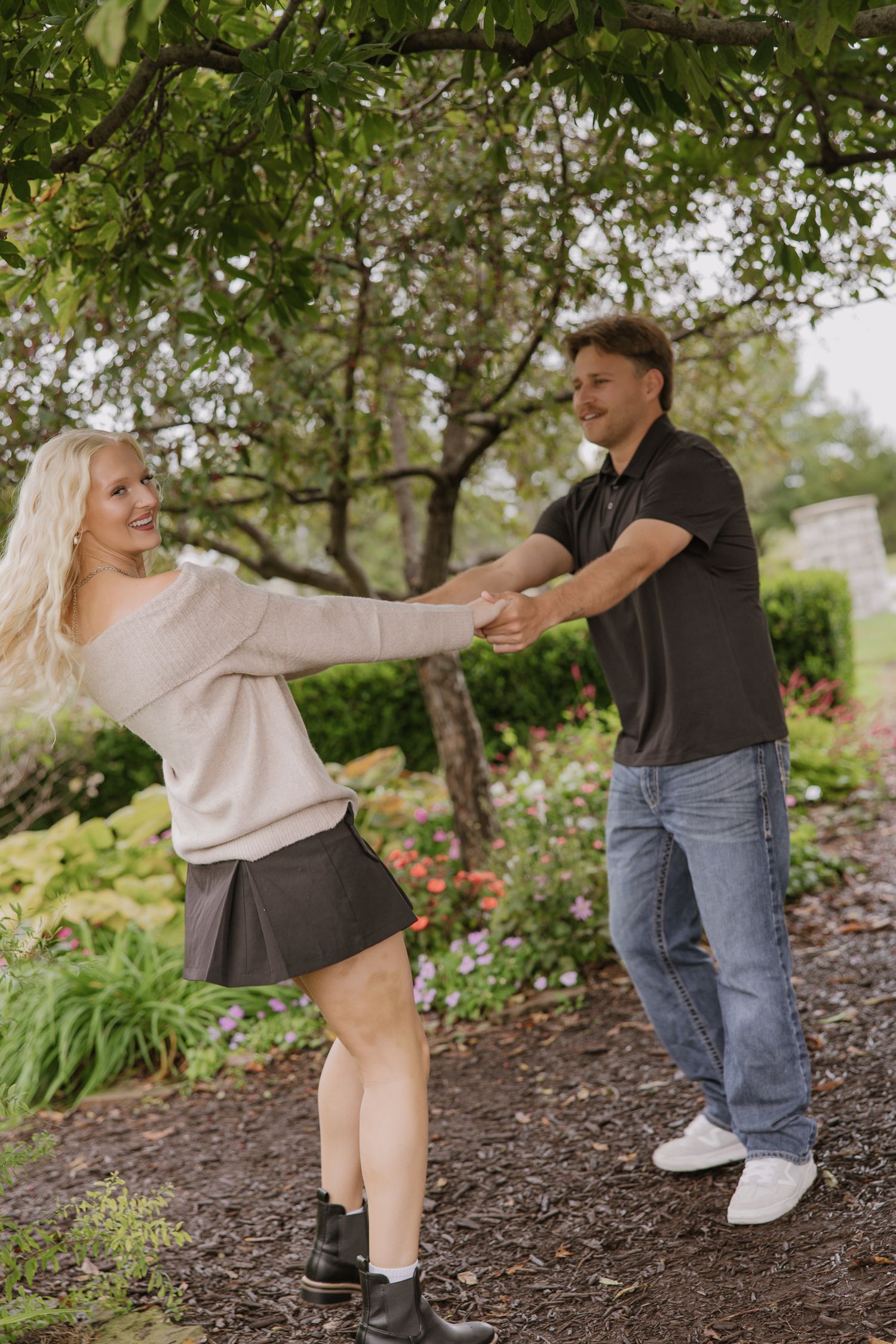 Couple dancing and having fun on a garden path under trees.
