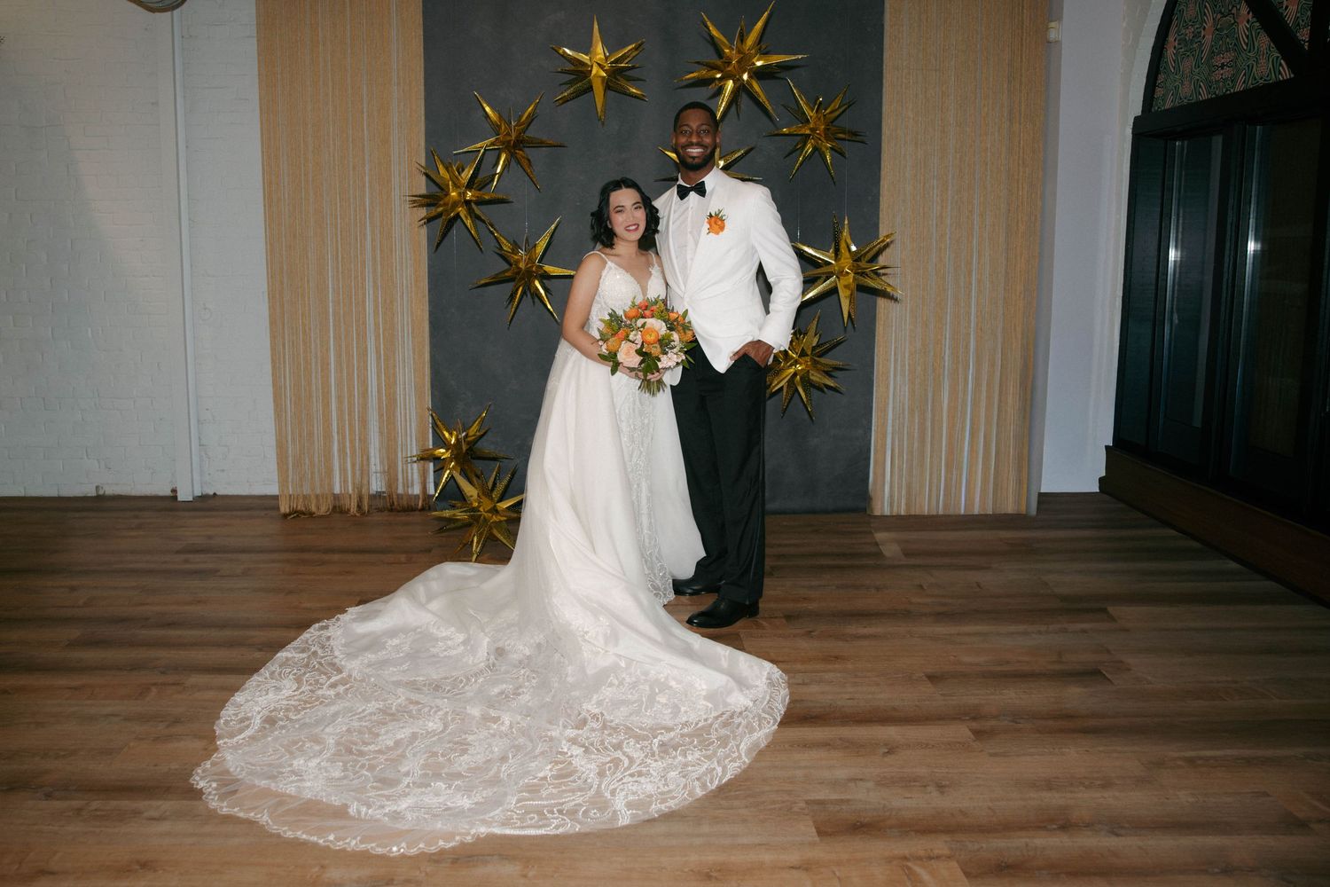 Wedding reception venue decorated with gold star decorations and wooden flooring.