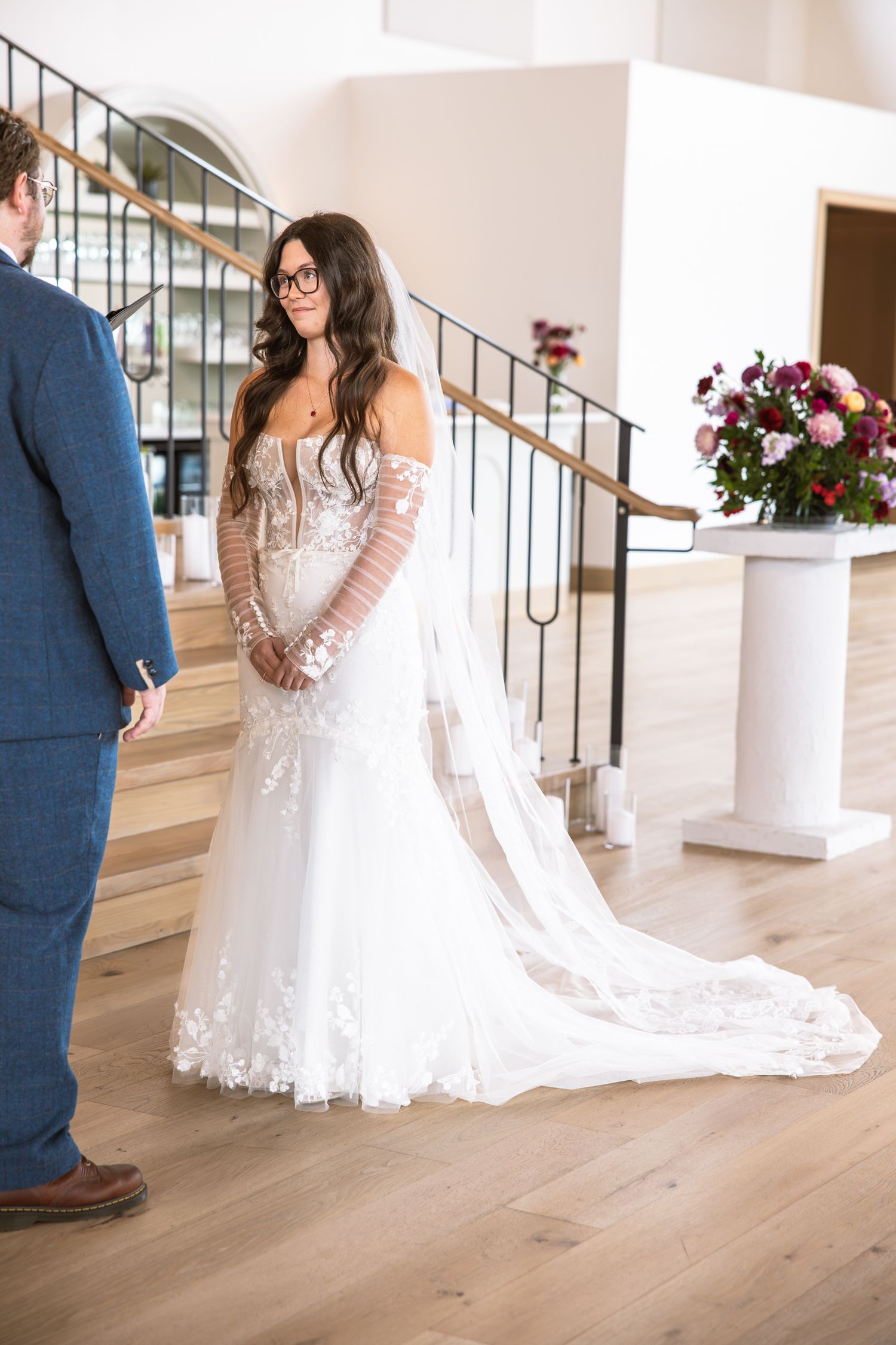 Elegant bridal gown with lace details and train photographed in modern venue.