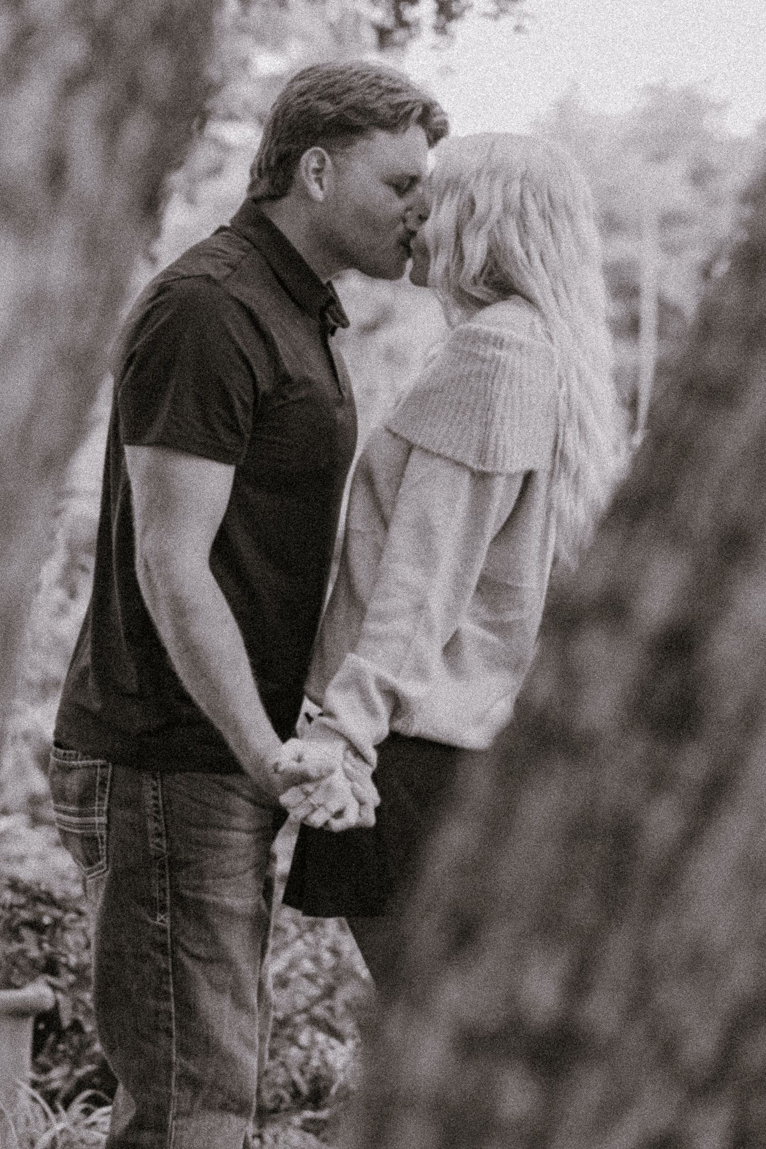 Intimate black and white portrait of a couple sharing a tender moment in nature.