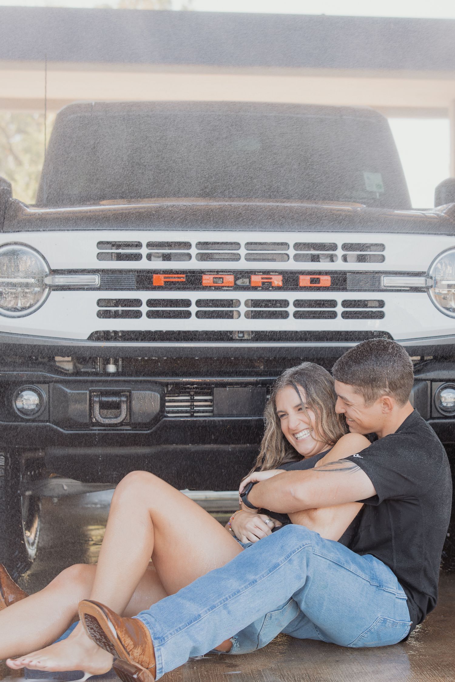 Intimate portrait of couple sitting together in front of Ford Bronco grille.