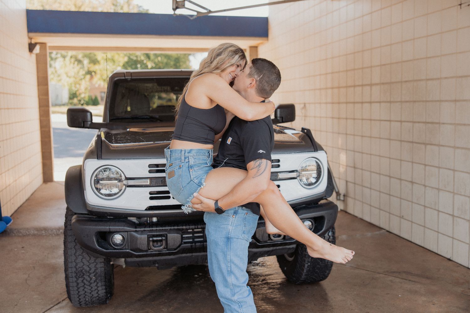 Intimate moment between couple in casual wear near parked vehicle.