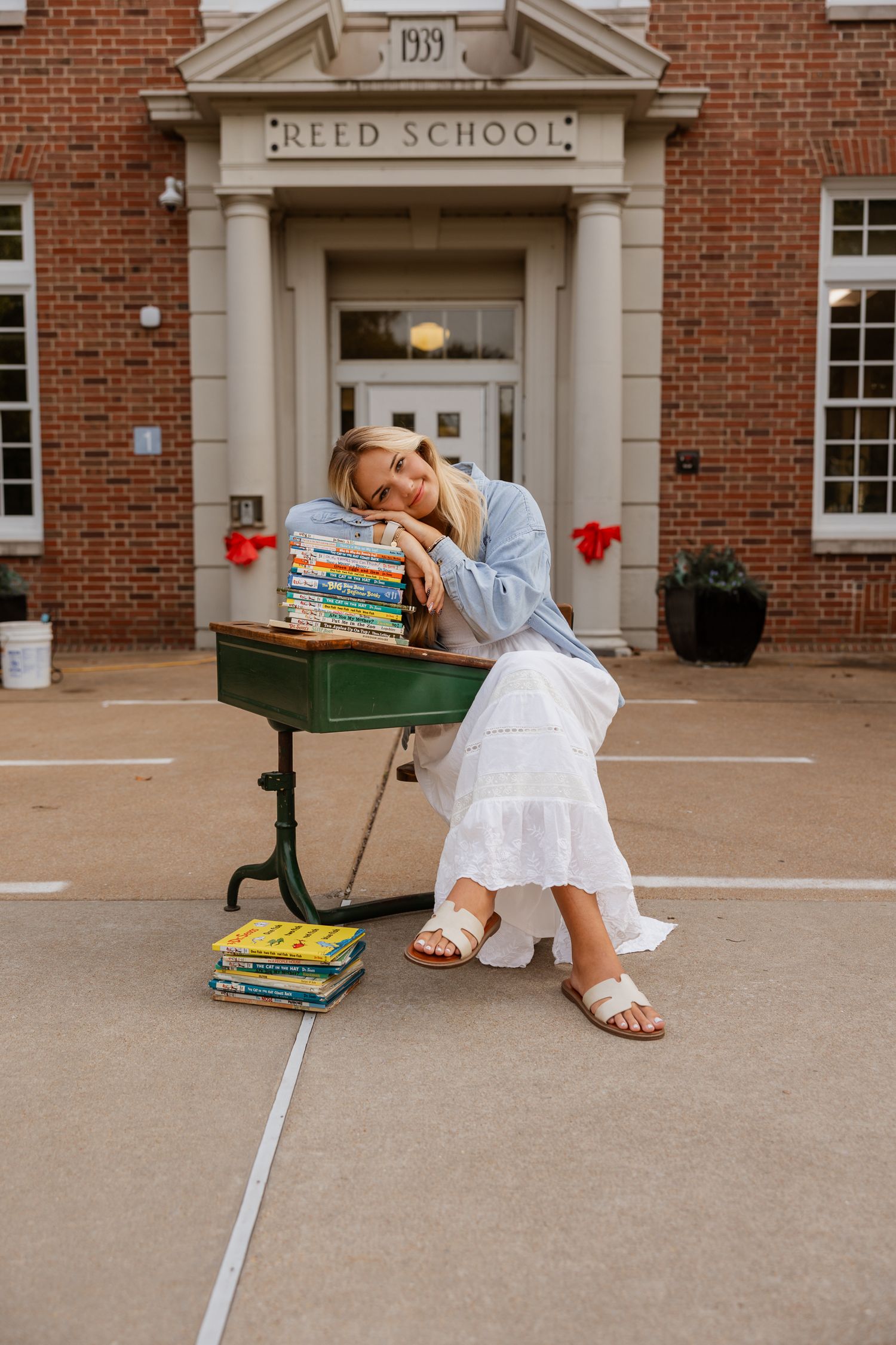 A student lounges with books outside Reed School's brick facade with white columns and red accents.