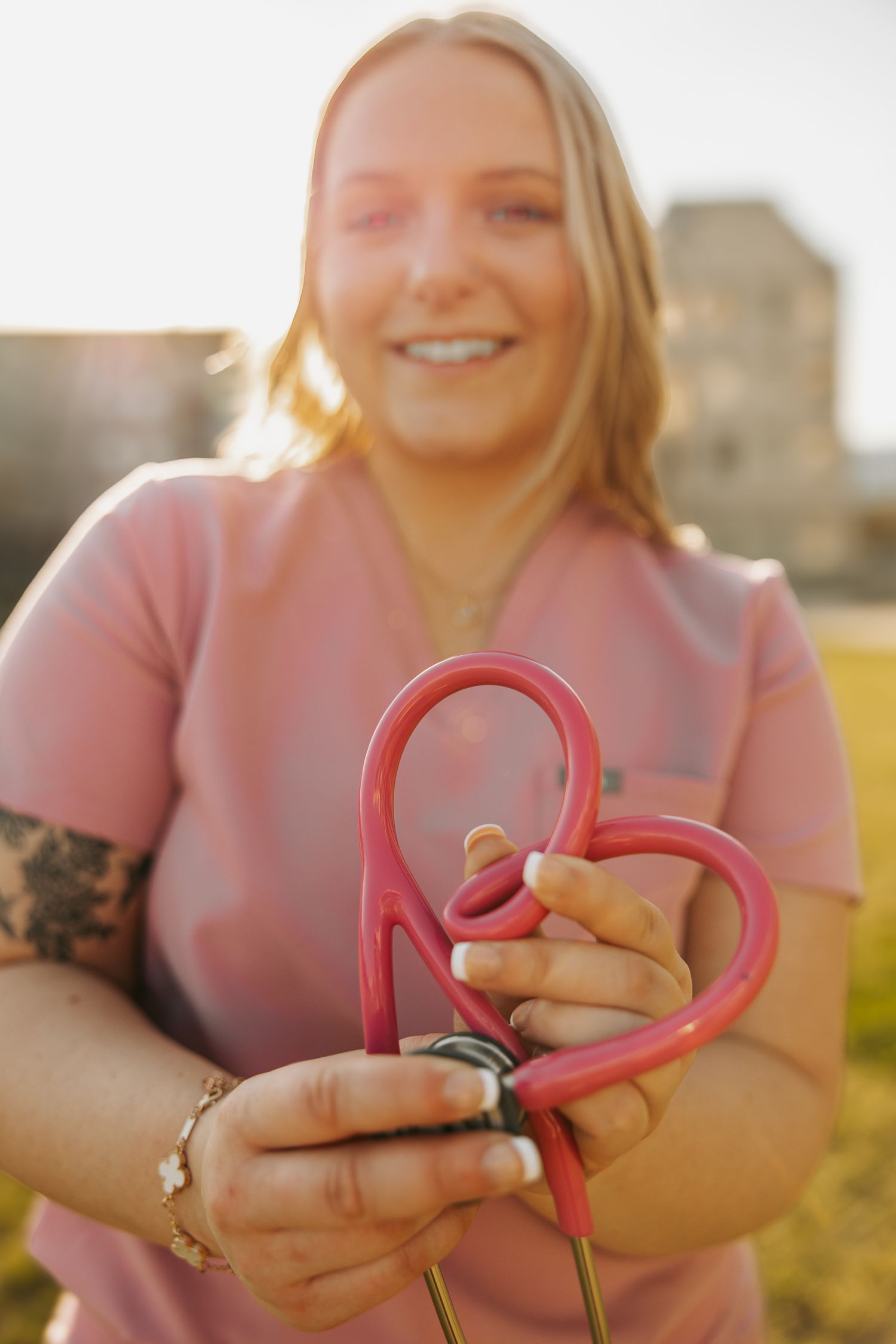 Person holding pink heart-shaped object in warm sunset lighting.