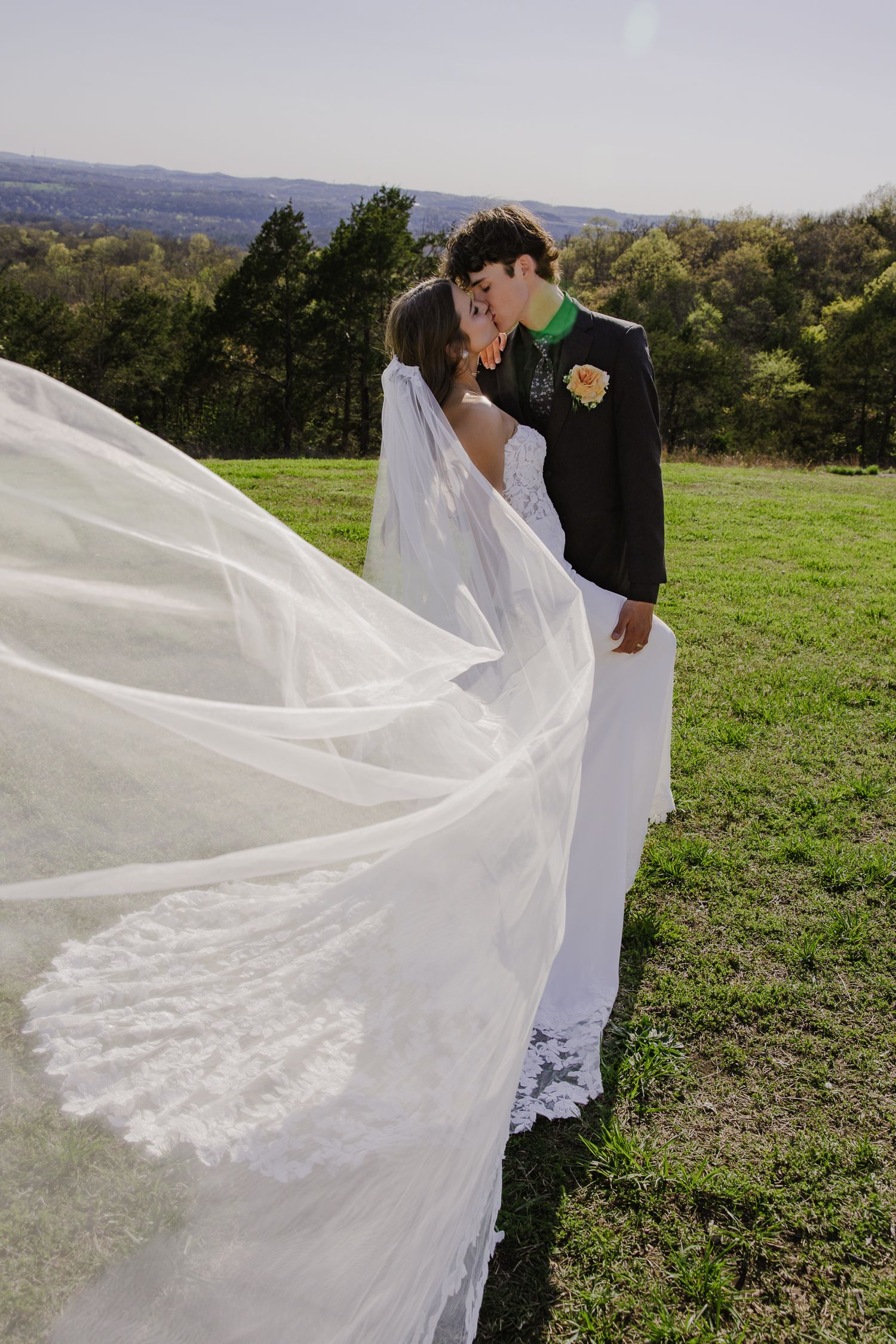Flowing white wedding veil catches the breeze against a scenic hillside backdrop.