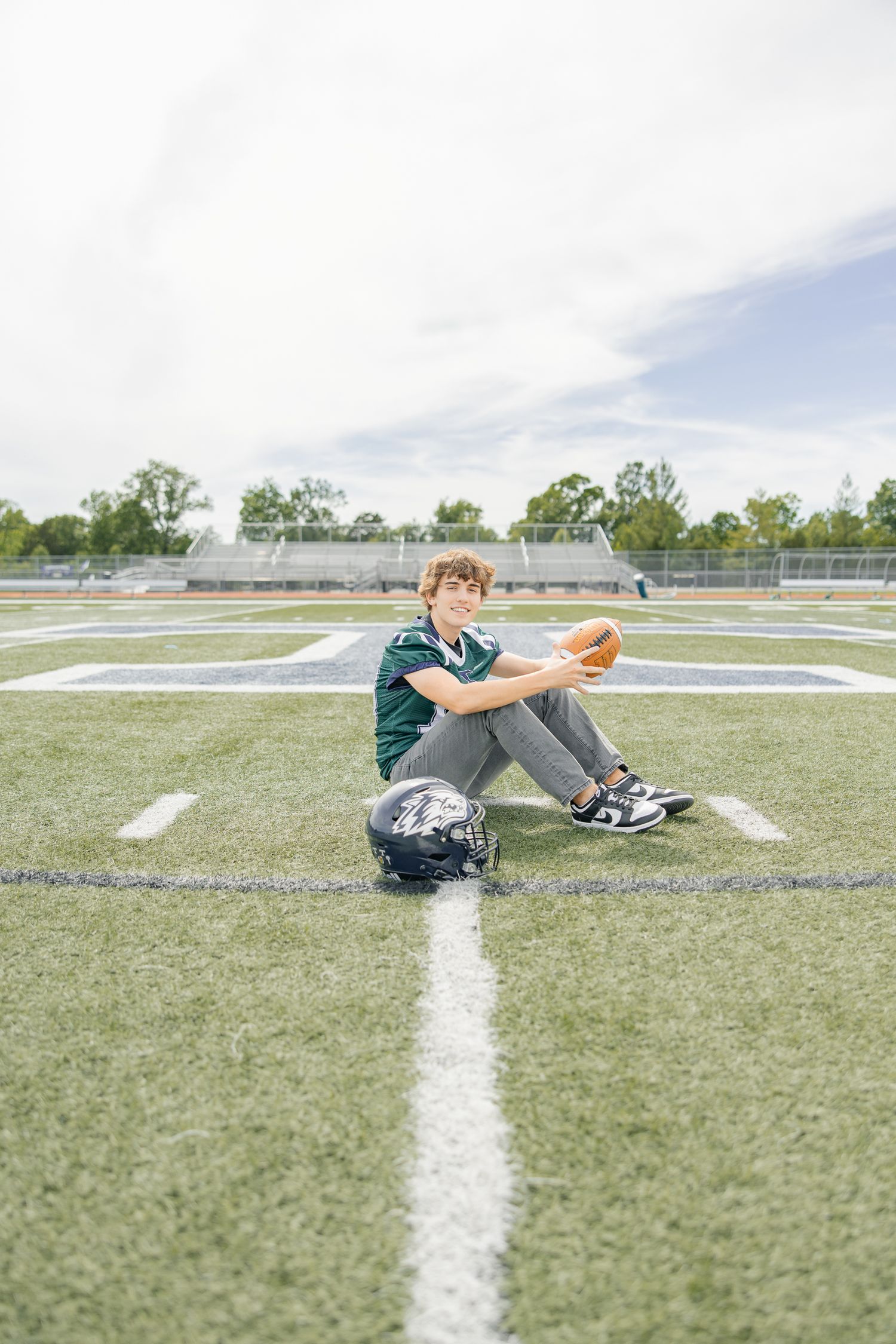 Sequence of player sitting on football field practicing with ball.