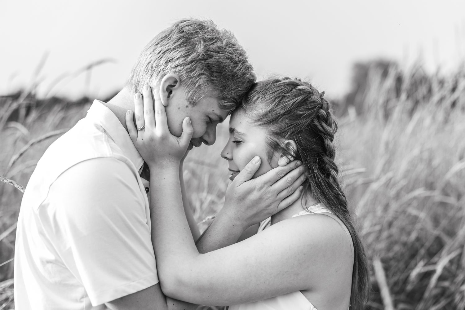 Black and white portraits of couple sharing tender moments in natural setting.