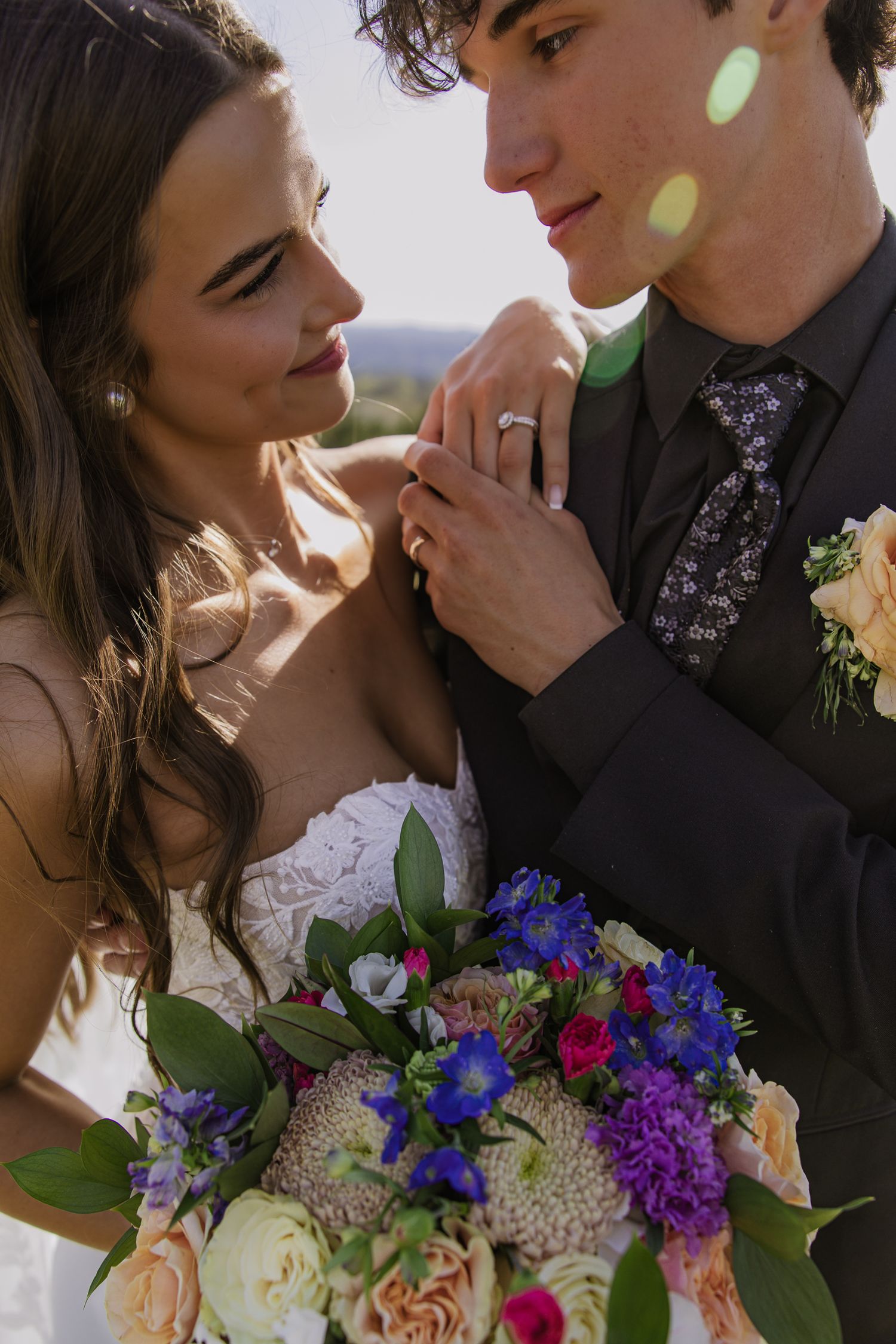 Romantic wedding portrait with vibrant blue and purple bouquet in soft lighting.