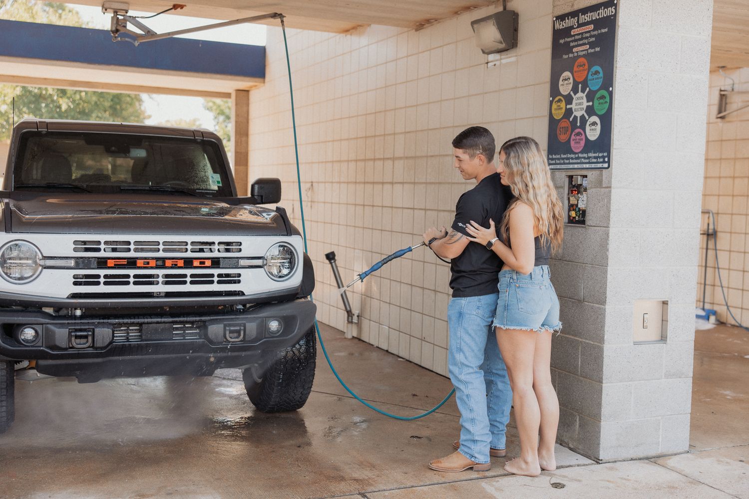 People at a self-service car wash station with trucks and cleaning equipment visible.