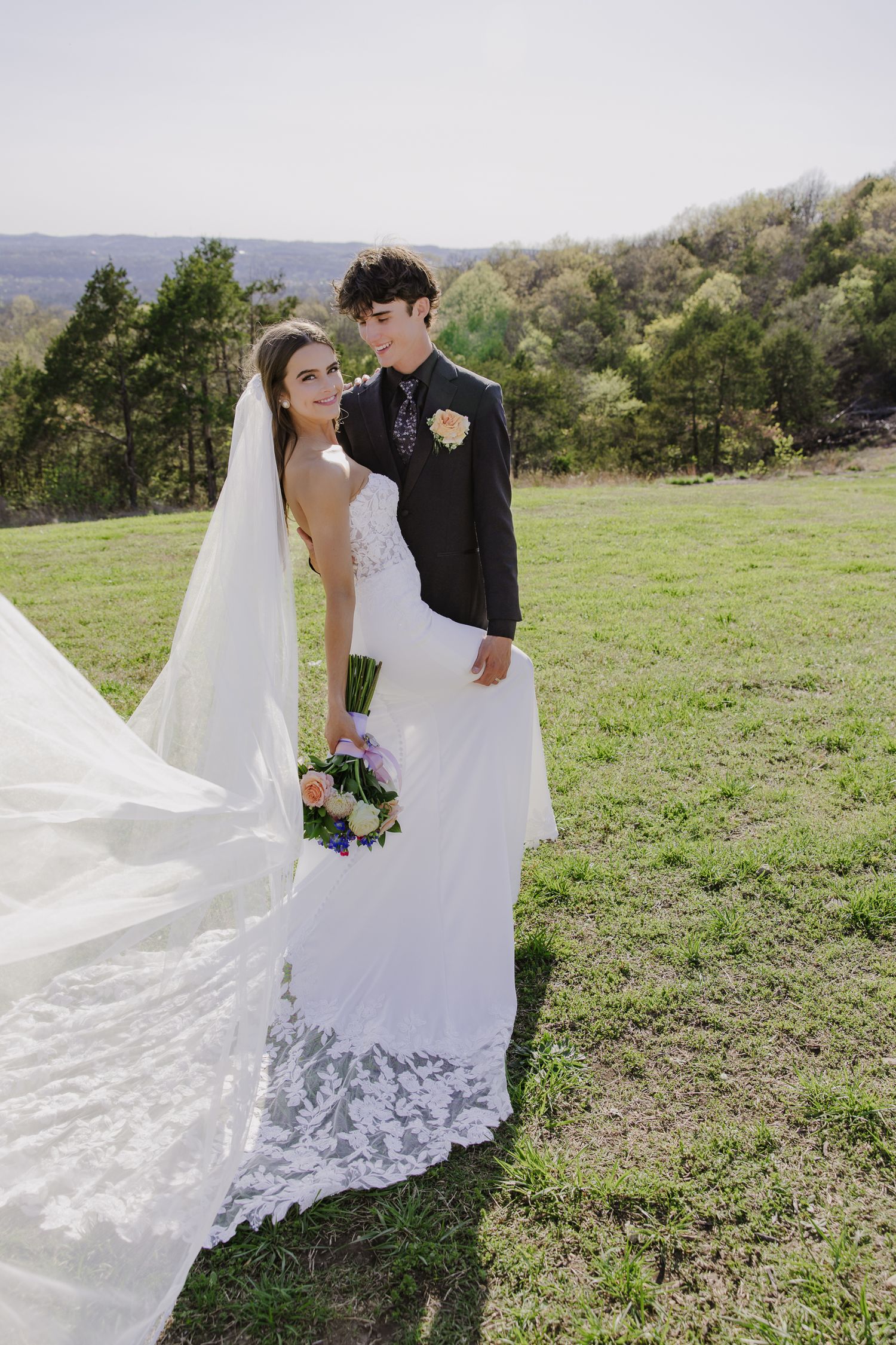 Scenic outdoor wedding portrait with mountain views and flowing white veil.
