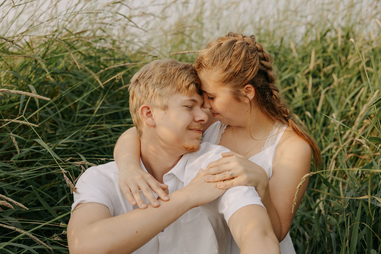 Intimate couple portraits captured in a natural setting with tall grass swaying in the background.