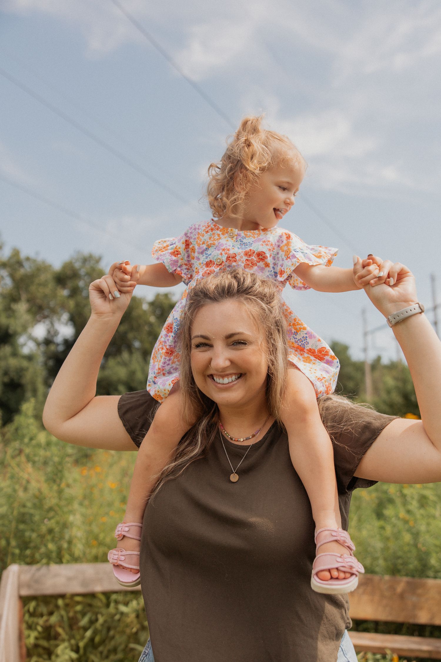 Playful piggyback ride captured in a sunny field with wildflowers and trees.