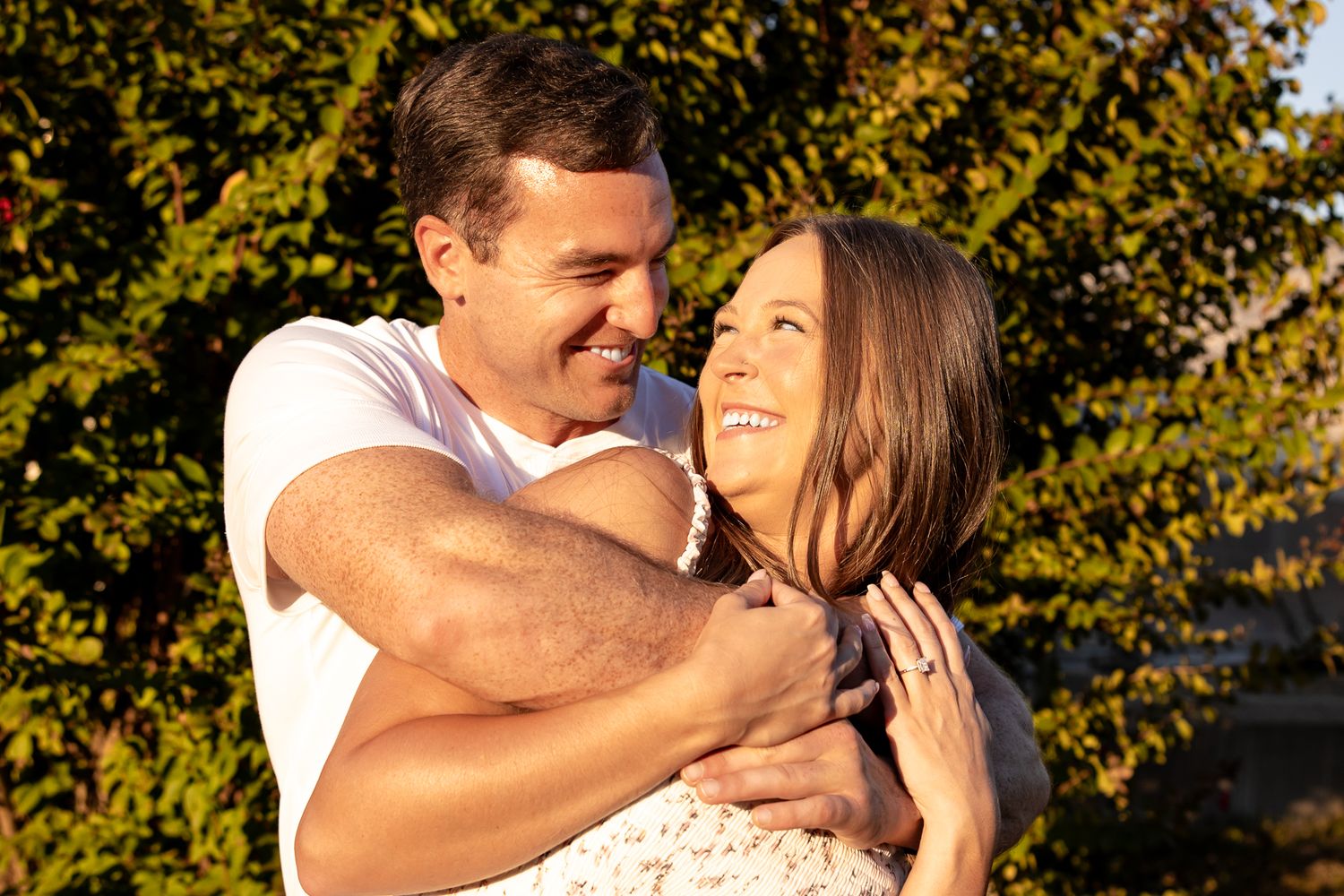 Couple shares joyful embraces in golden autumn sunlight.