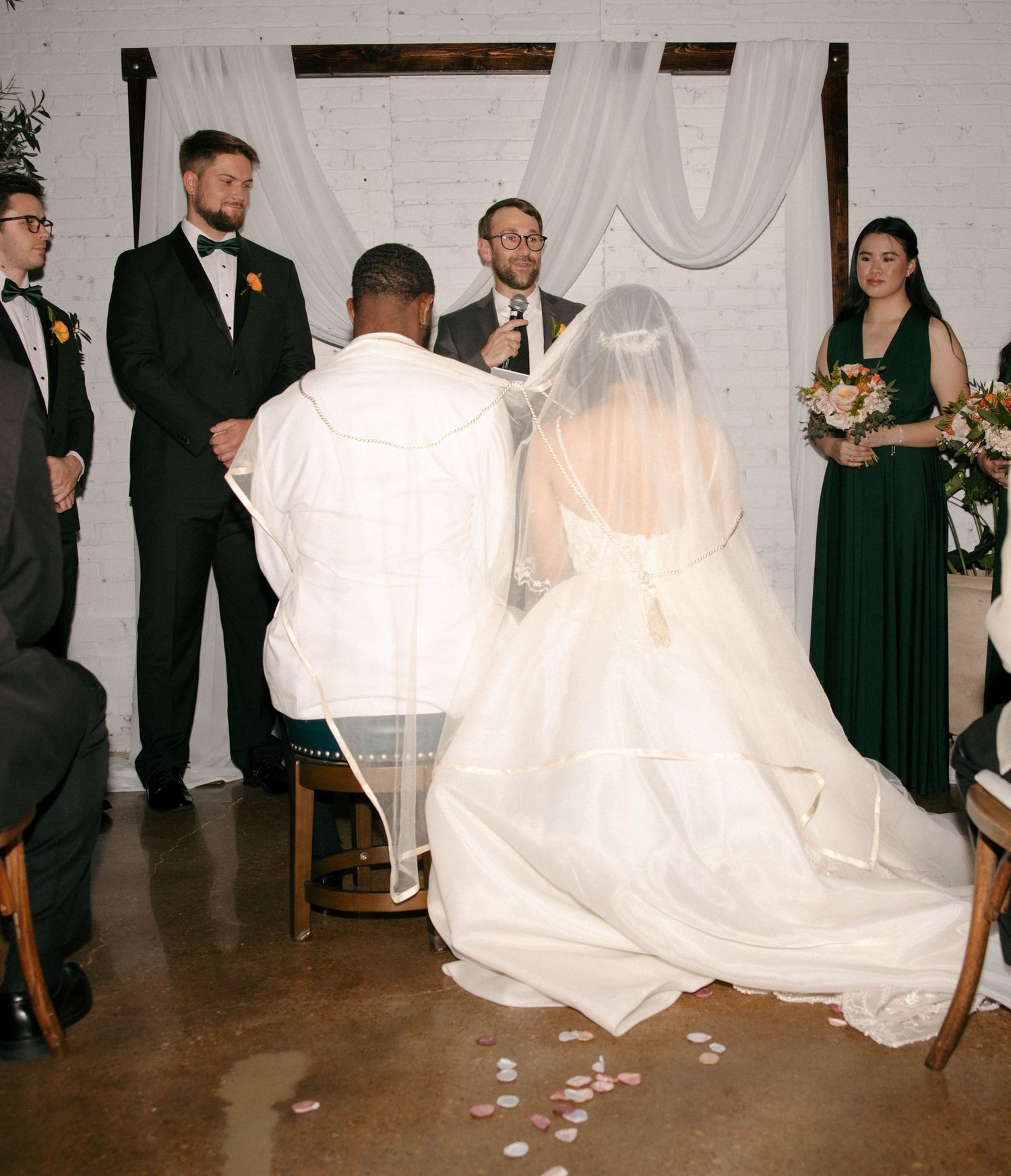 Wedding reception in a minimalist venue with white drapes and dark flooring.