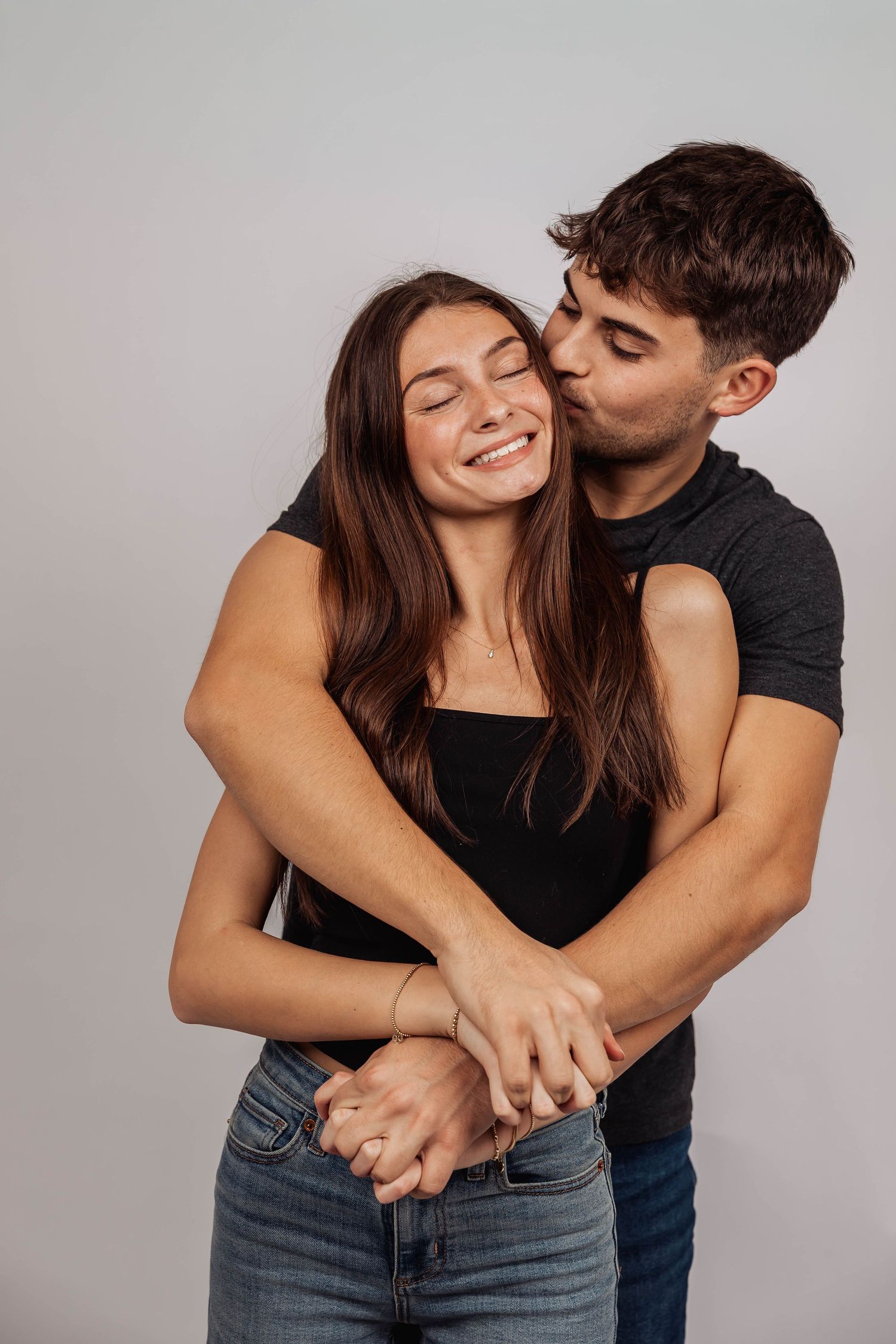 Affectionate couple sharing tender moments in casual studio photoshoot.