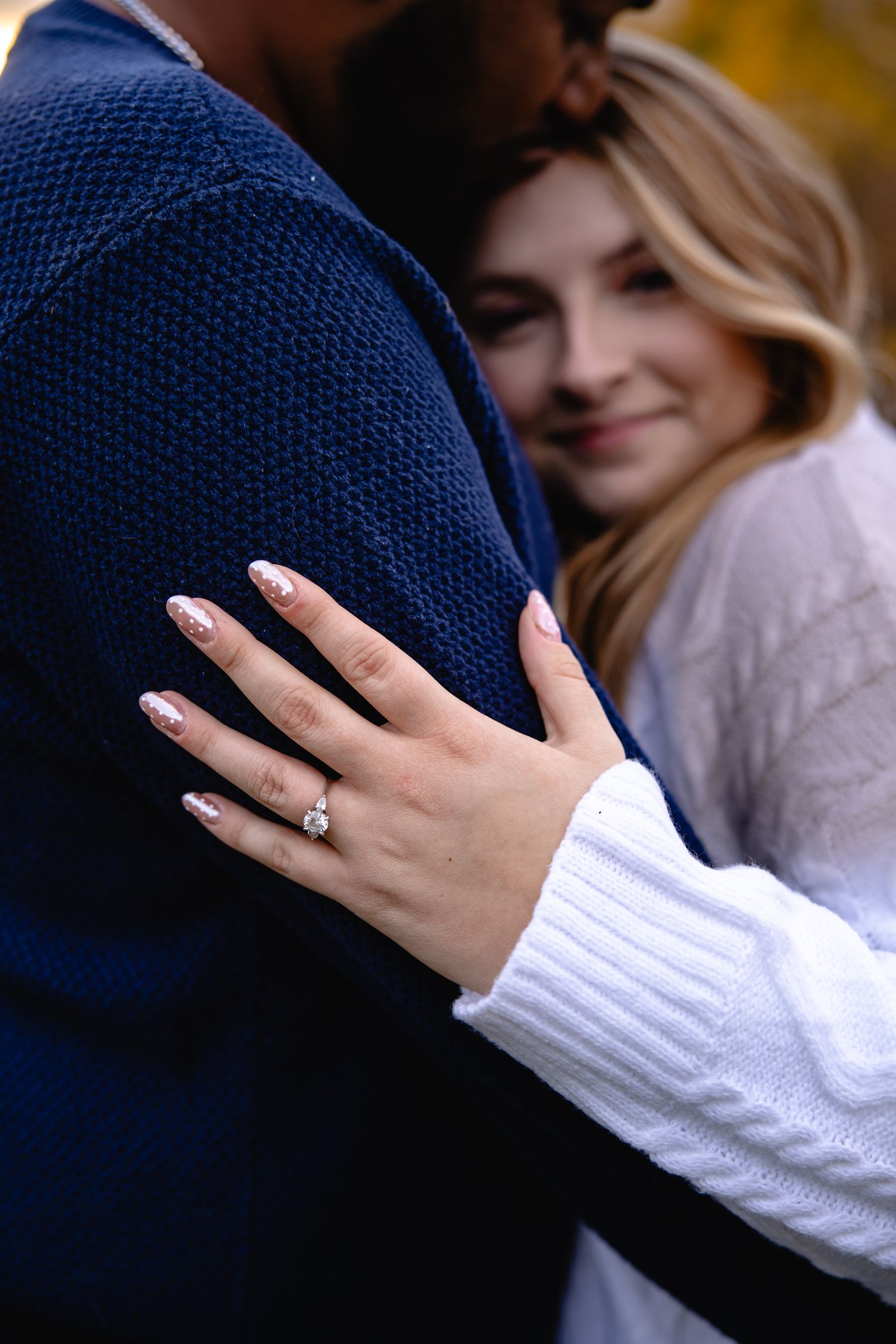 Close-up engagement photo showing hands with new ring during an intimate embrace.