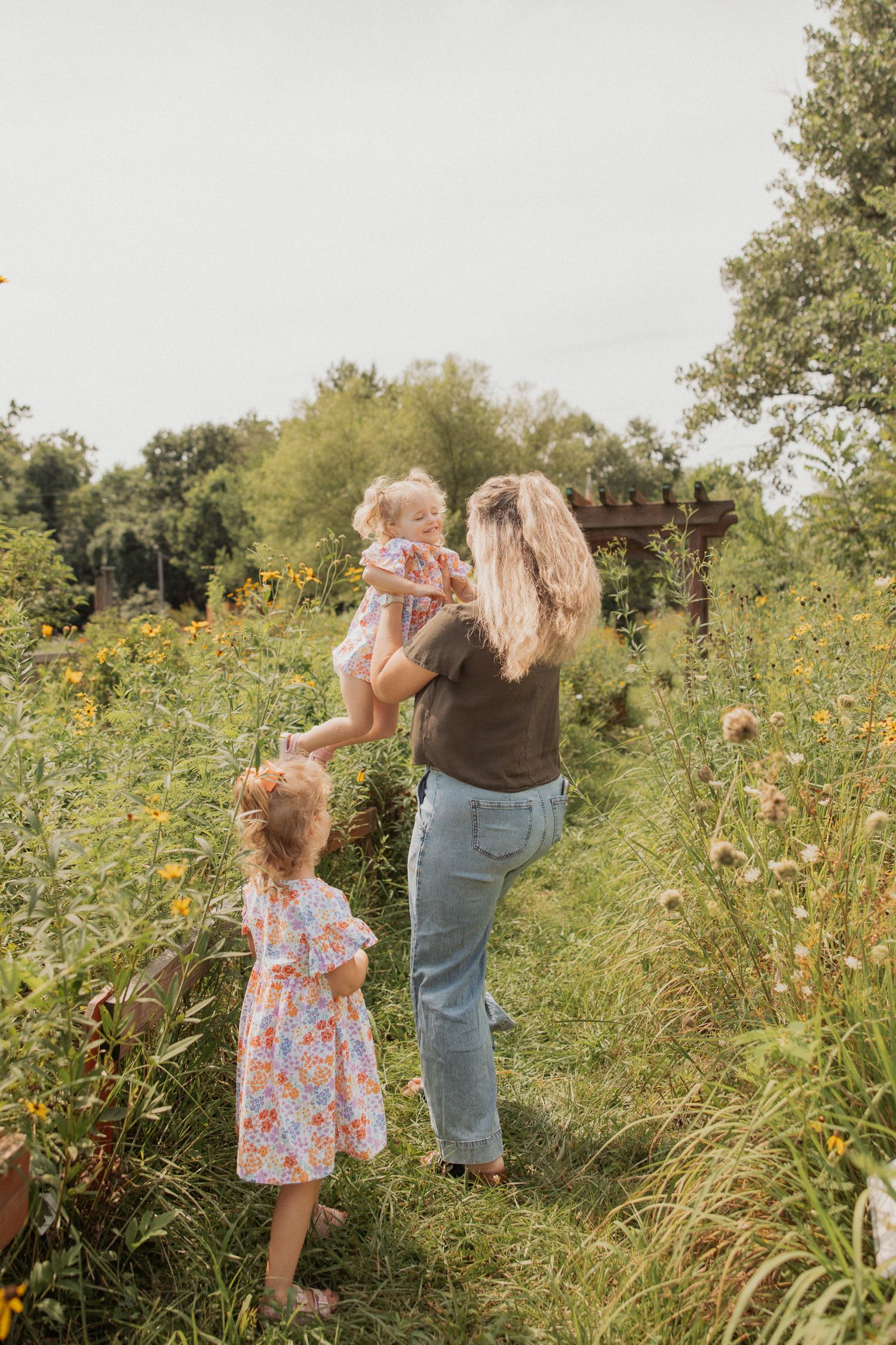 Candid moment captured in a summer meadow with matching floral outfits among yellow wildflowers.