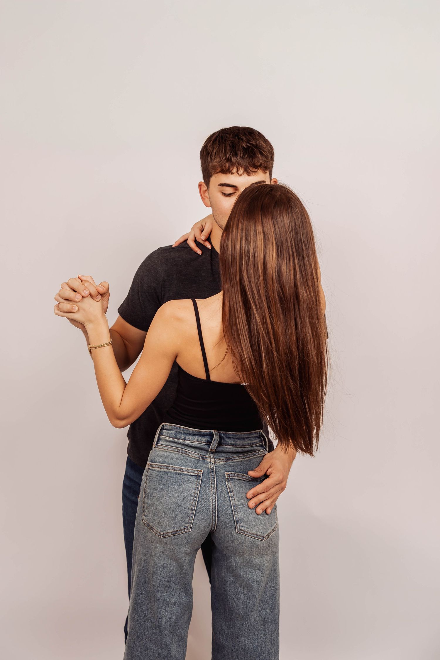 Couple in denim and black tops sharing romantic dance poses.