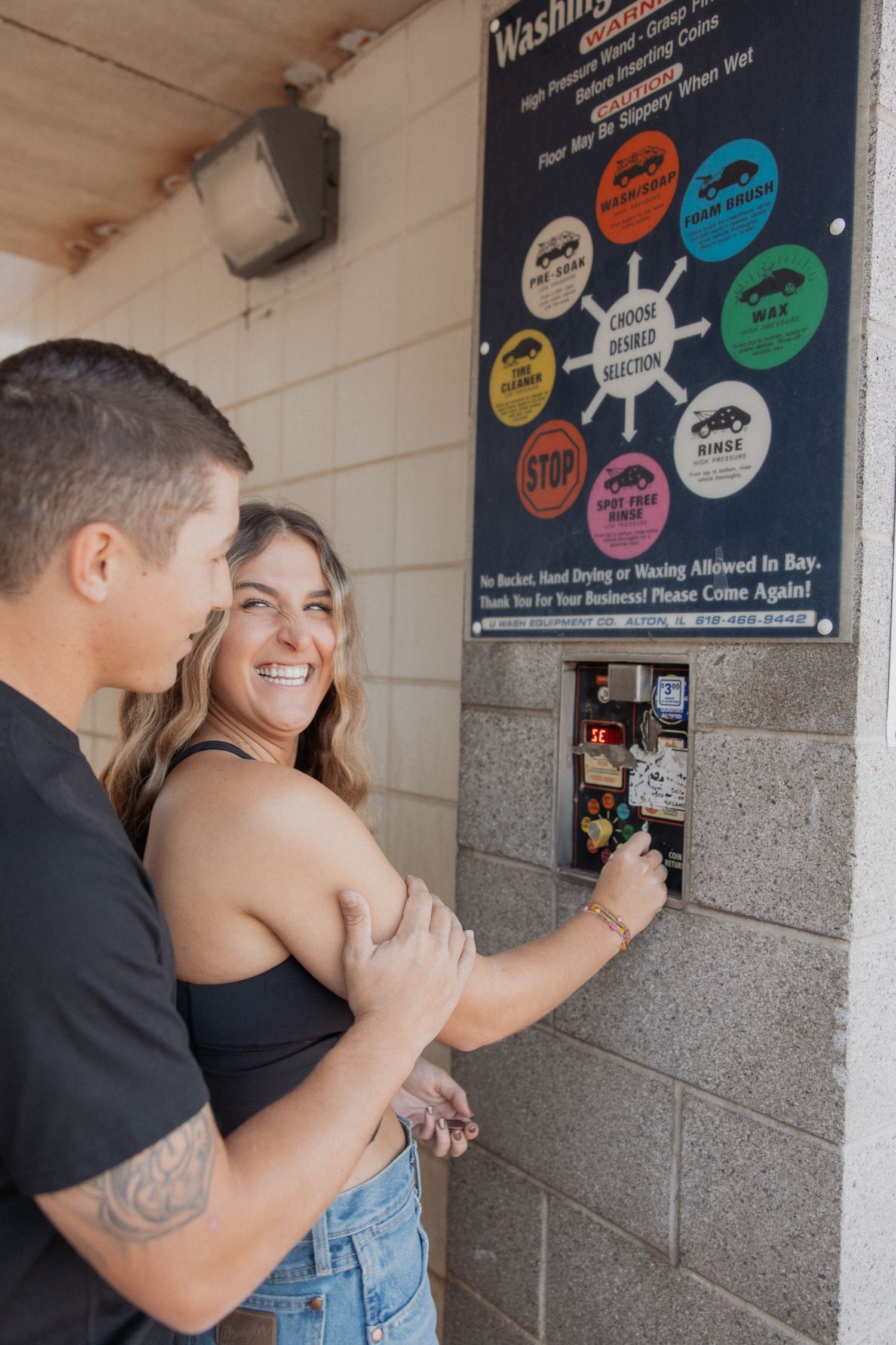Couple looking at car wash menu board together while sharing a laugh.