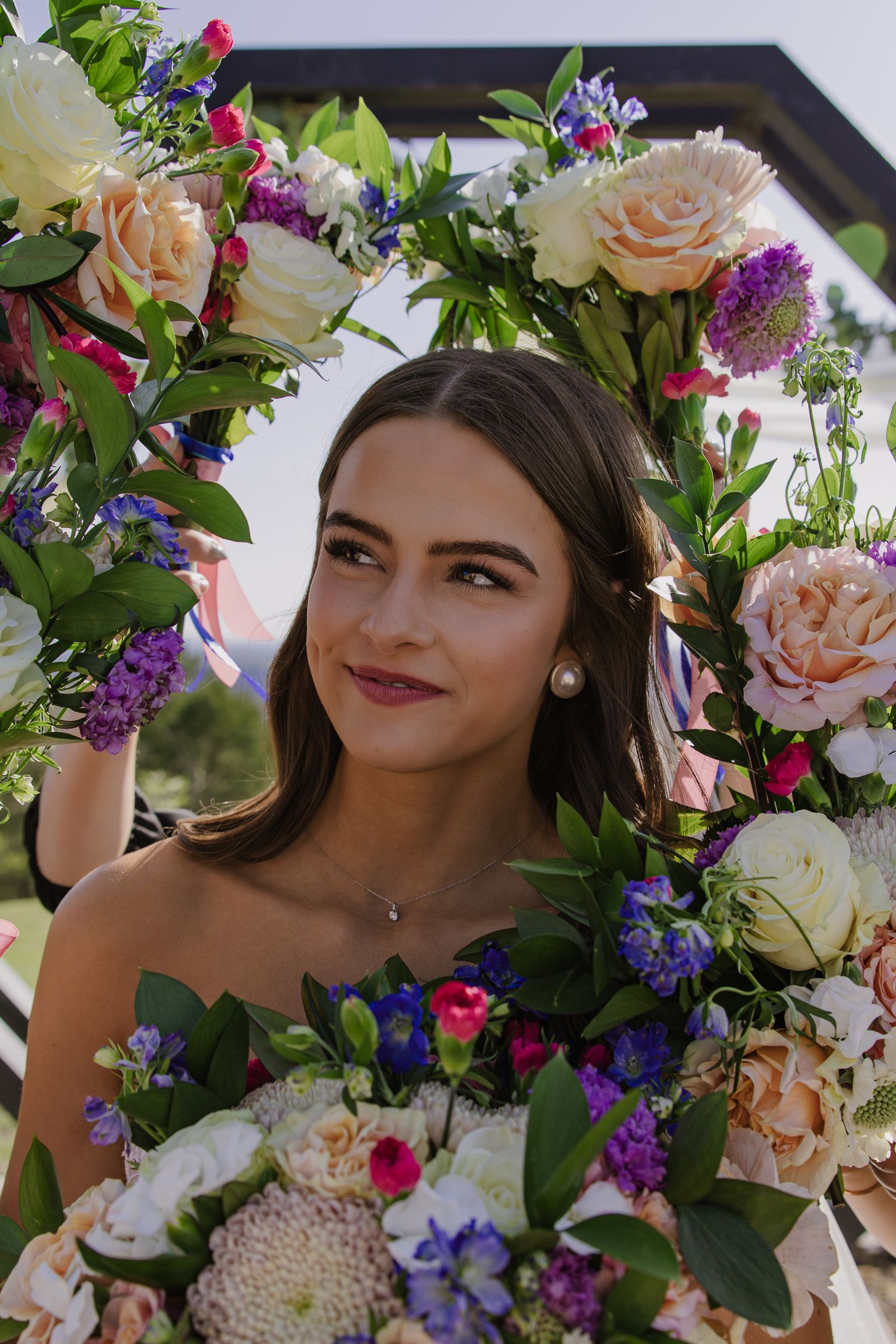 Beautiful floral crown with peach roses, purple flowers, and greenery against a dark background.