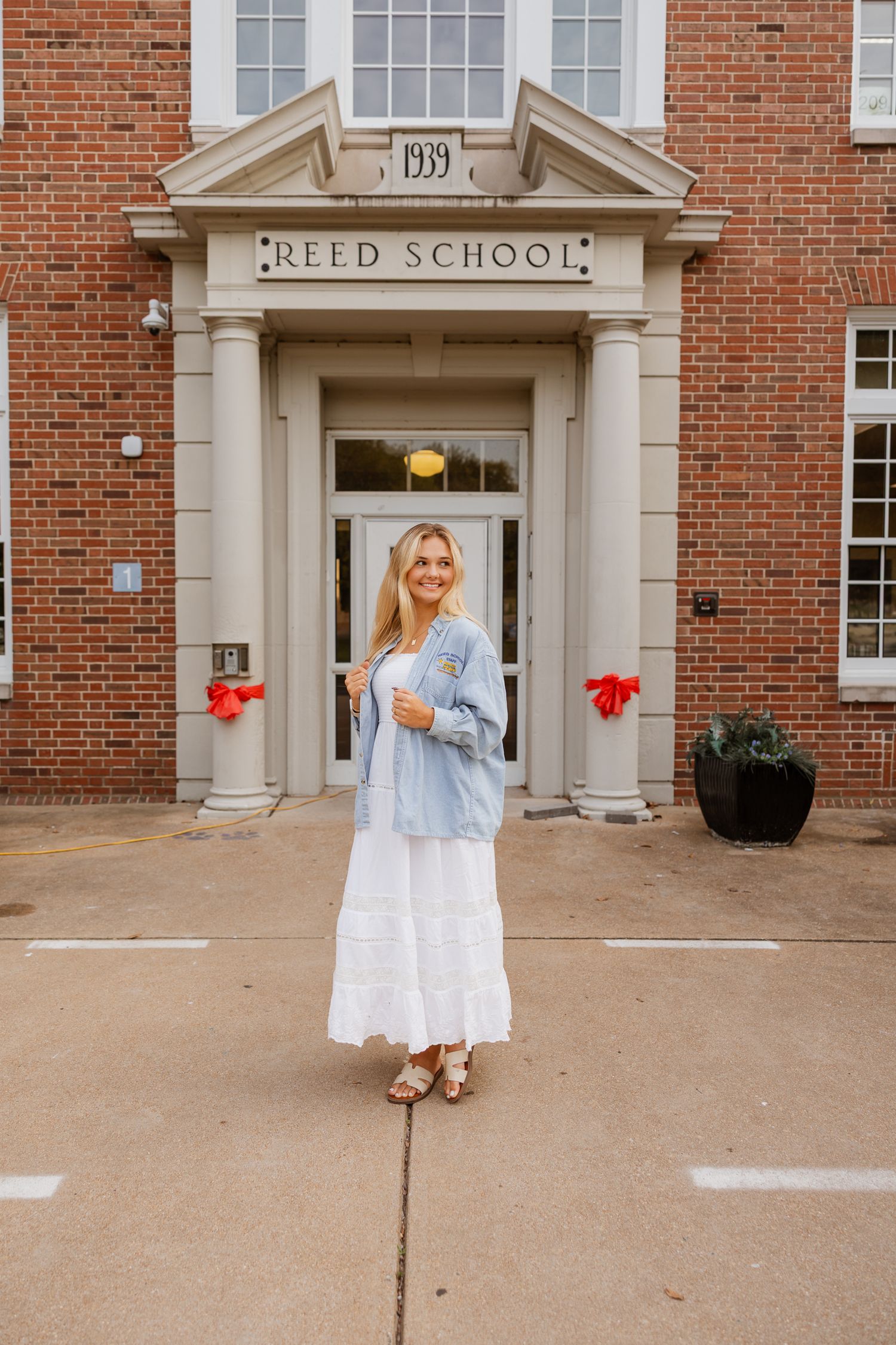 Summer fashion shoot featuring white dress outside traditional brick school building.
