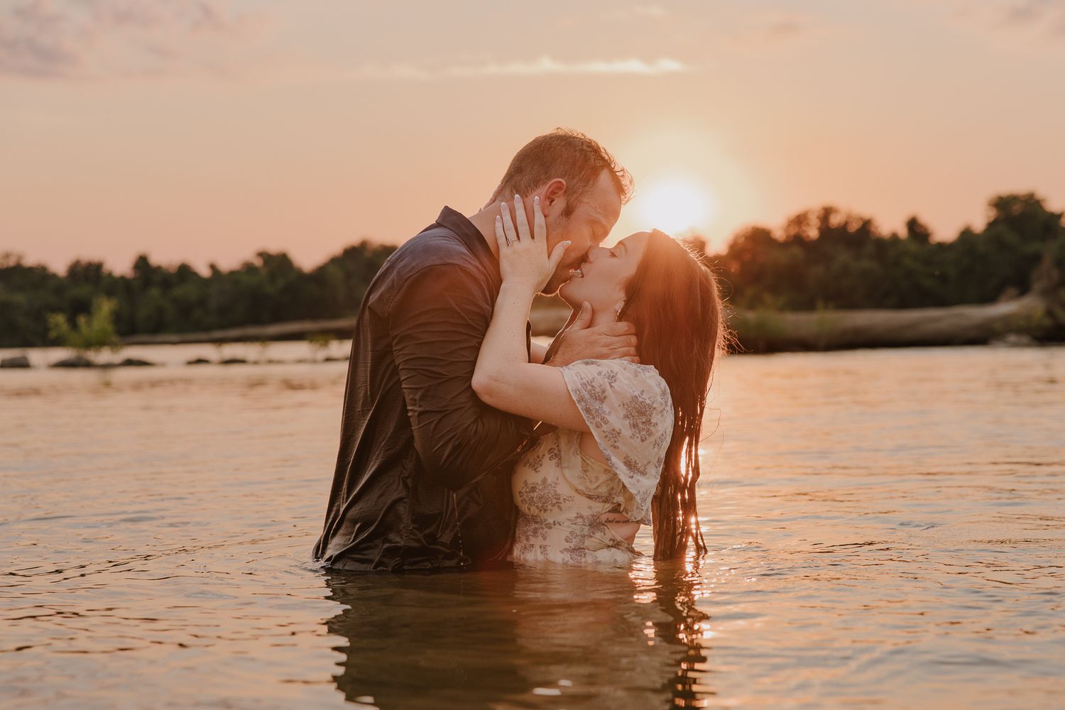 Silhouettes against golden sunset with water splashing during romantic photoshoot.