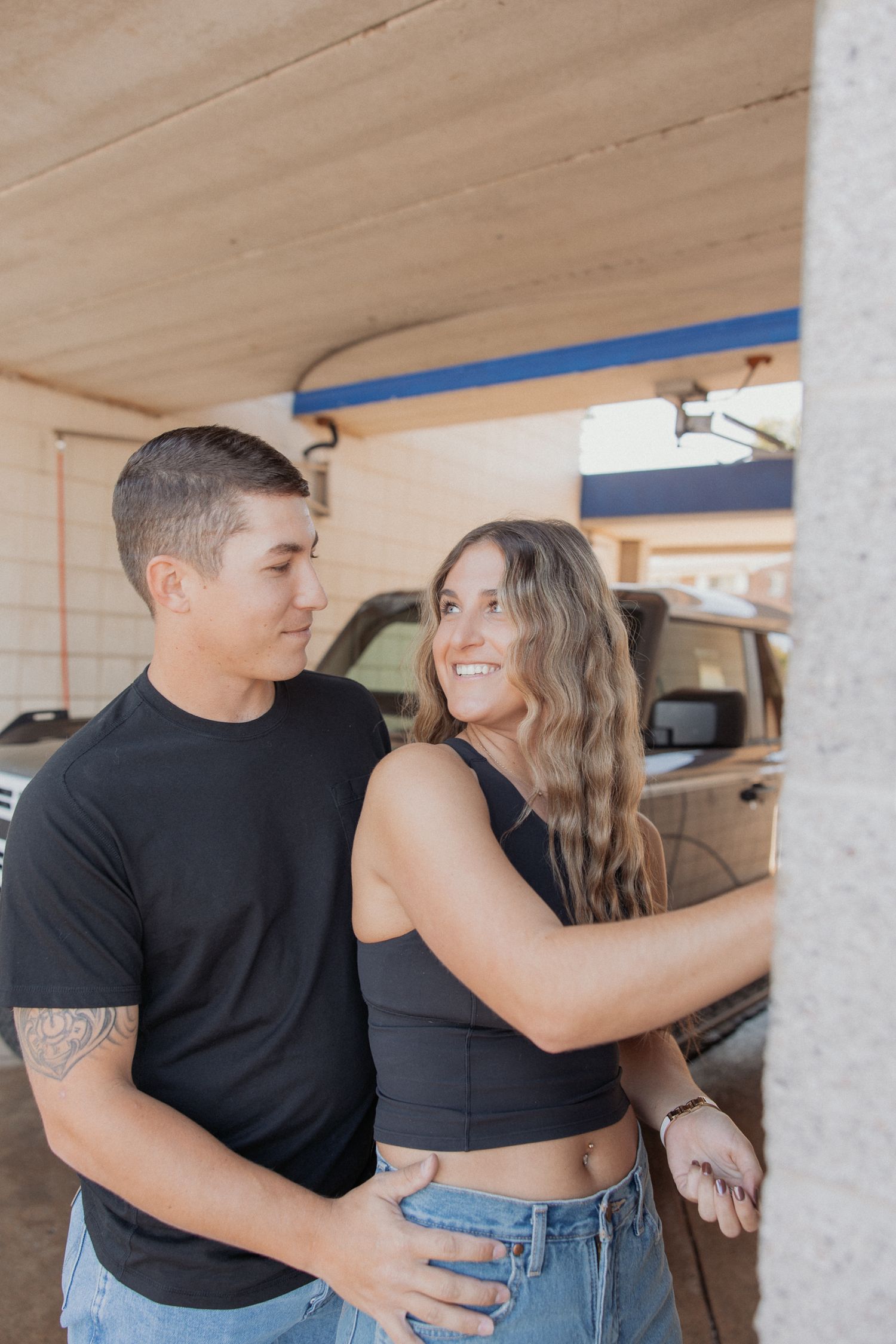 A couple sharing a tender moment in a covered parking area.