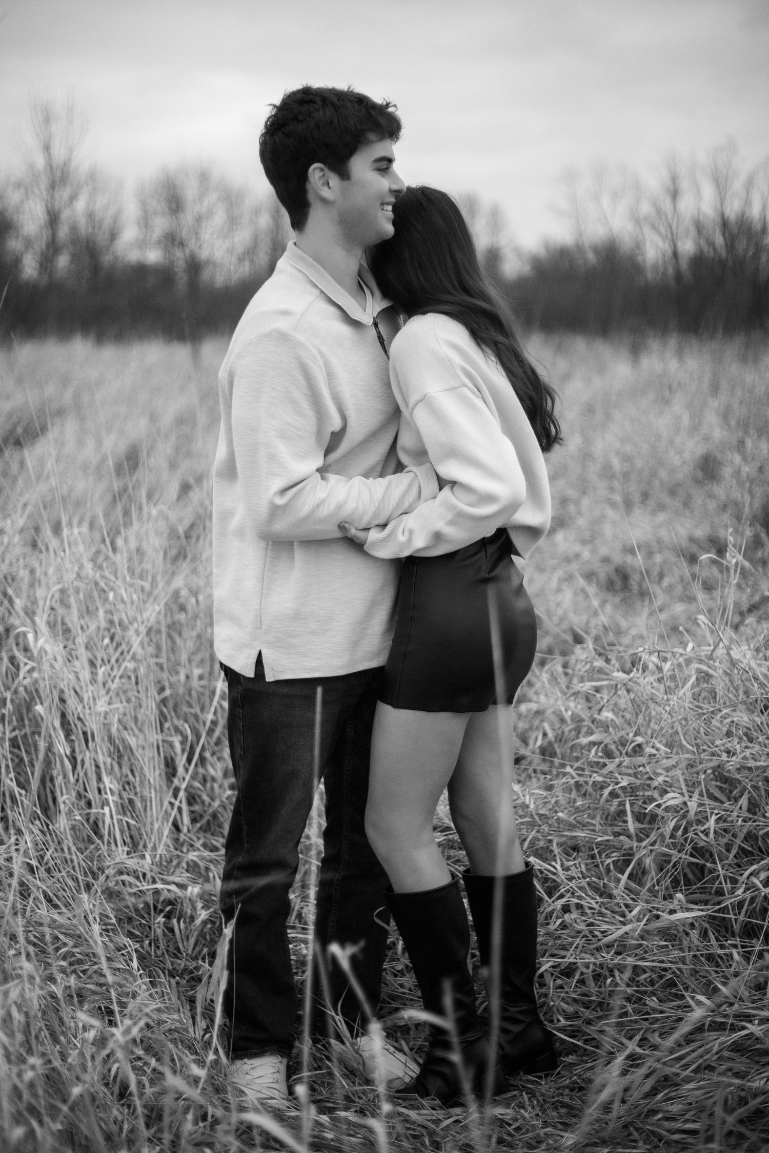 Black and white portrait series of a couple embracing in a rustic field setting.