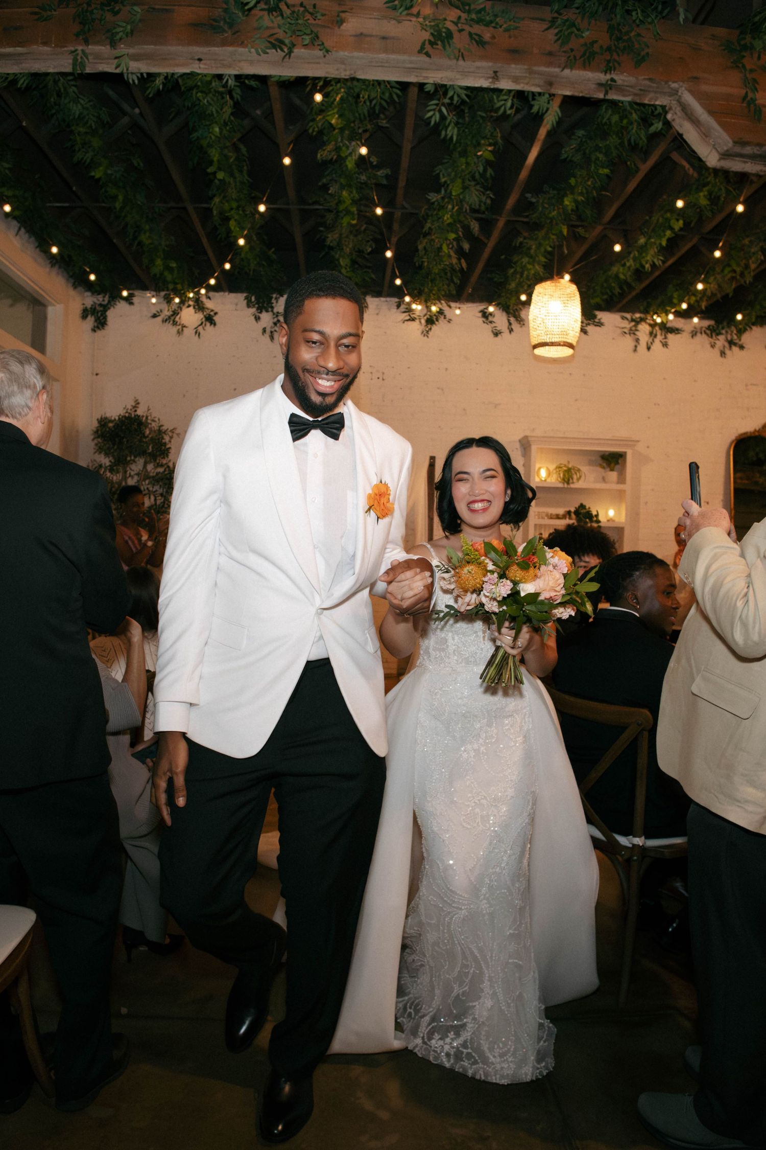 Wedding celebration with guests dancing and enjoying festivities in an indoor venue.