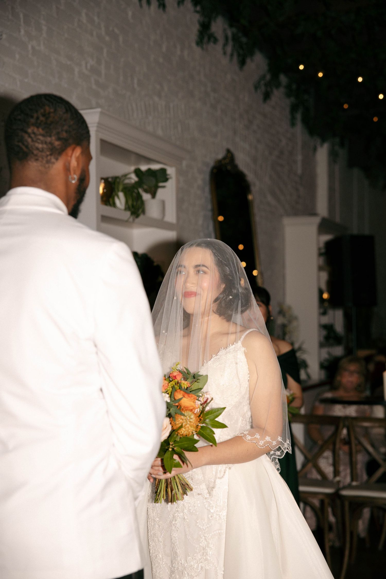 A wedding ceremony in progress with white decor and floral arrangements.