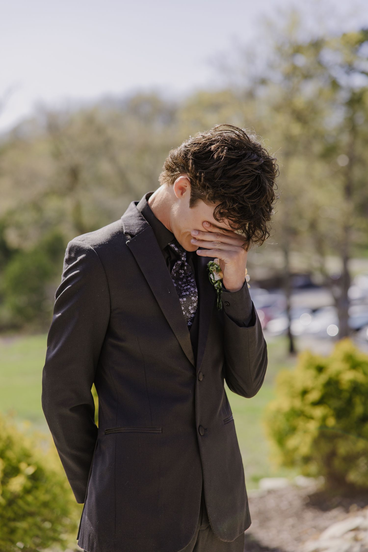 Person in dark suit shows emotional reaction during outdoor event.