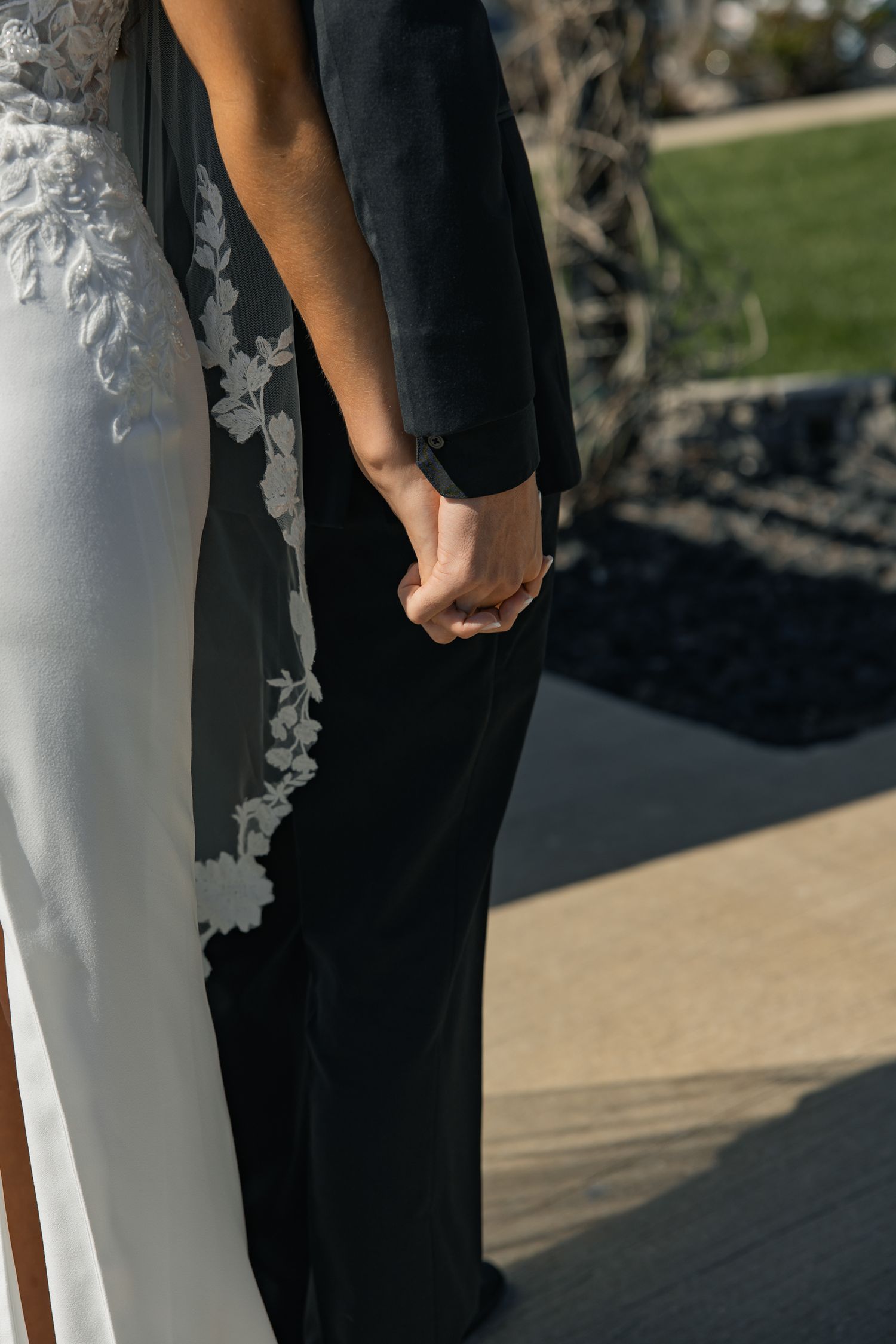 Close-up of newlyweds holding hands during outdoor wedding ceremony.