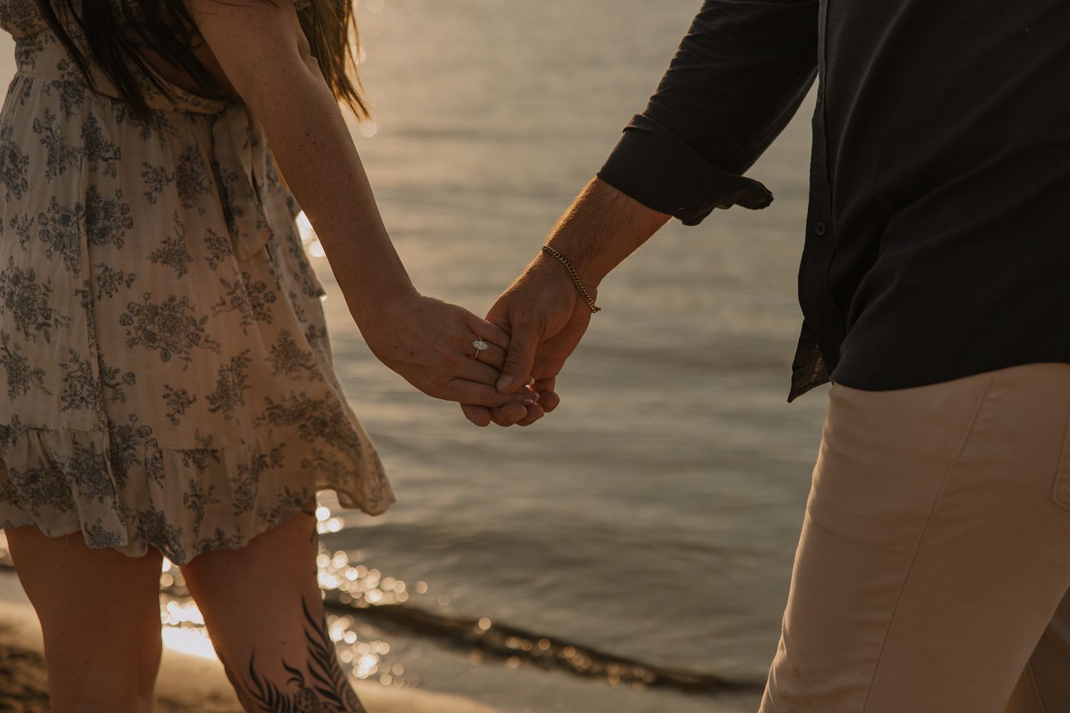 Close-up of hands holding during romantic beach photoshoot at dusk.