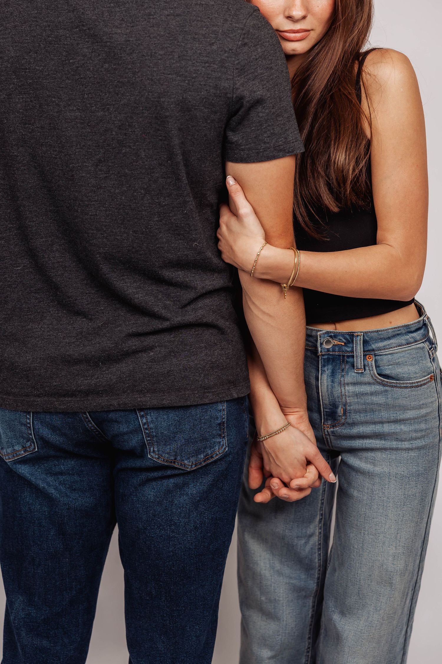 Close-up shot of two people in denim and dark tops against white backdrop.