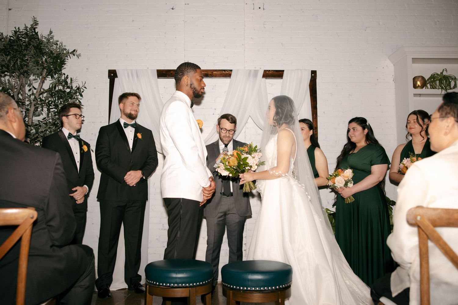 Wedding celebration with guests and wedding party gathered indoors at a reception venue.