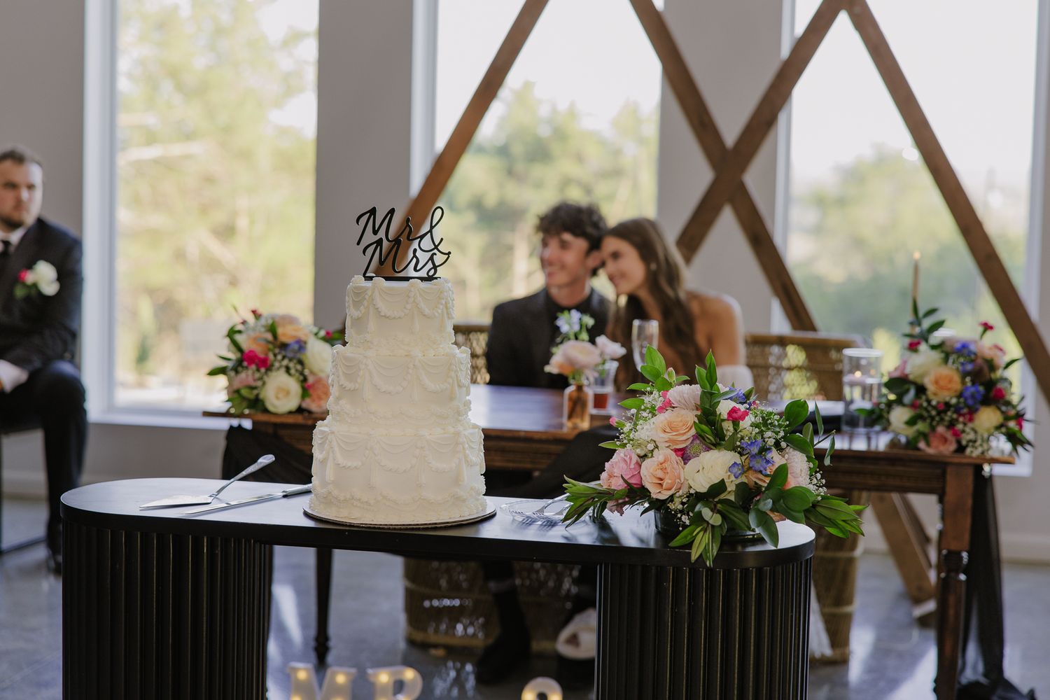 Wedding guests mingle and sign documents at elegantly decorated tables with floral centerpieces.