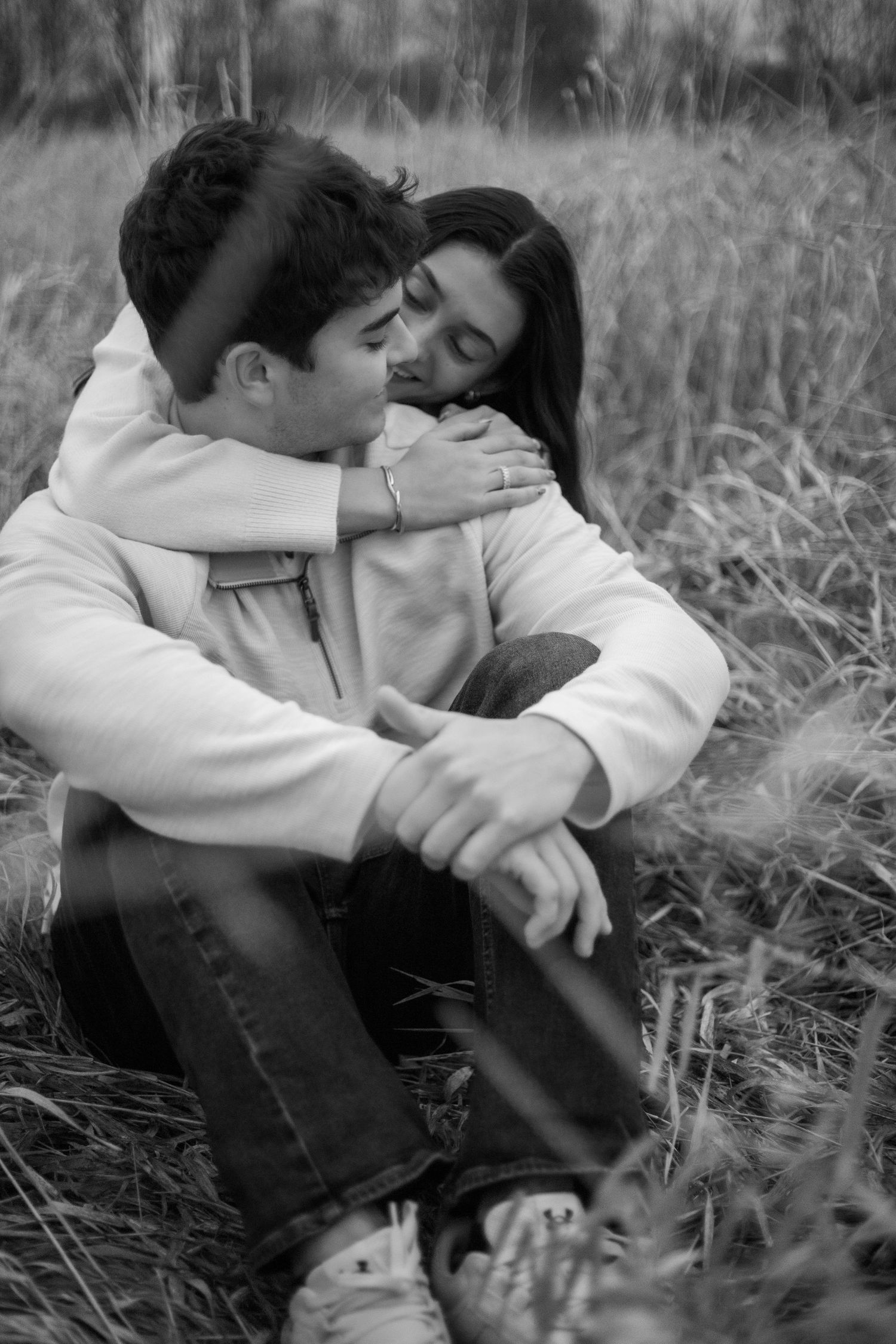 Intimate black and white photo sequence of a couple sharing tender moments in tall grass.