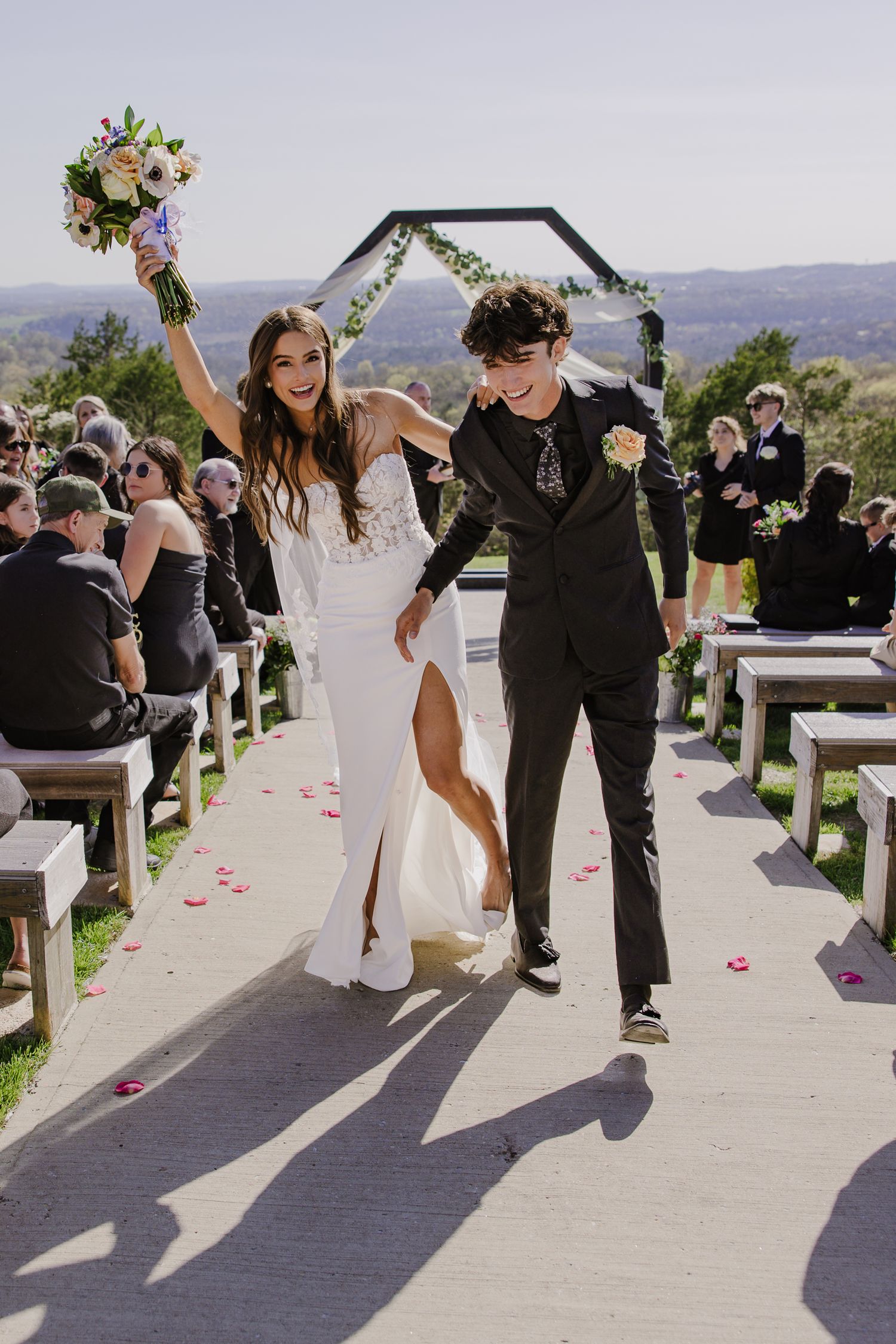 Newlyweds celebrating while walking down the aisle at an outdoor mountain wedding ceremony.