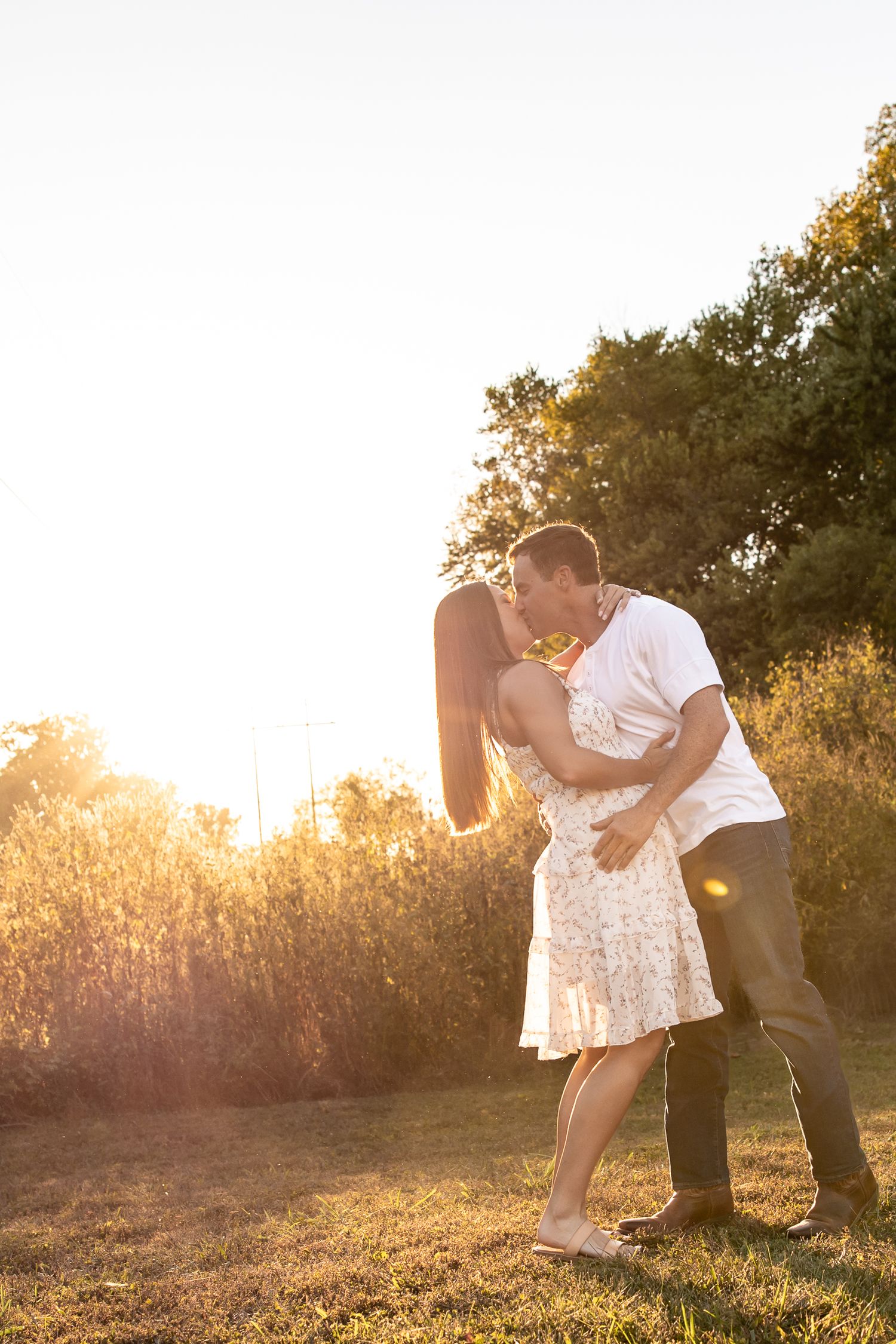 Romantic couple dances and dips in sunlit field at golden hour.