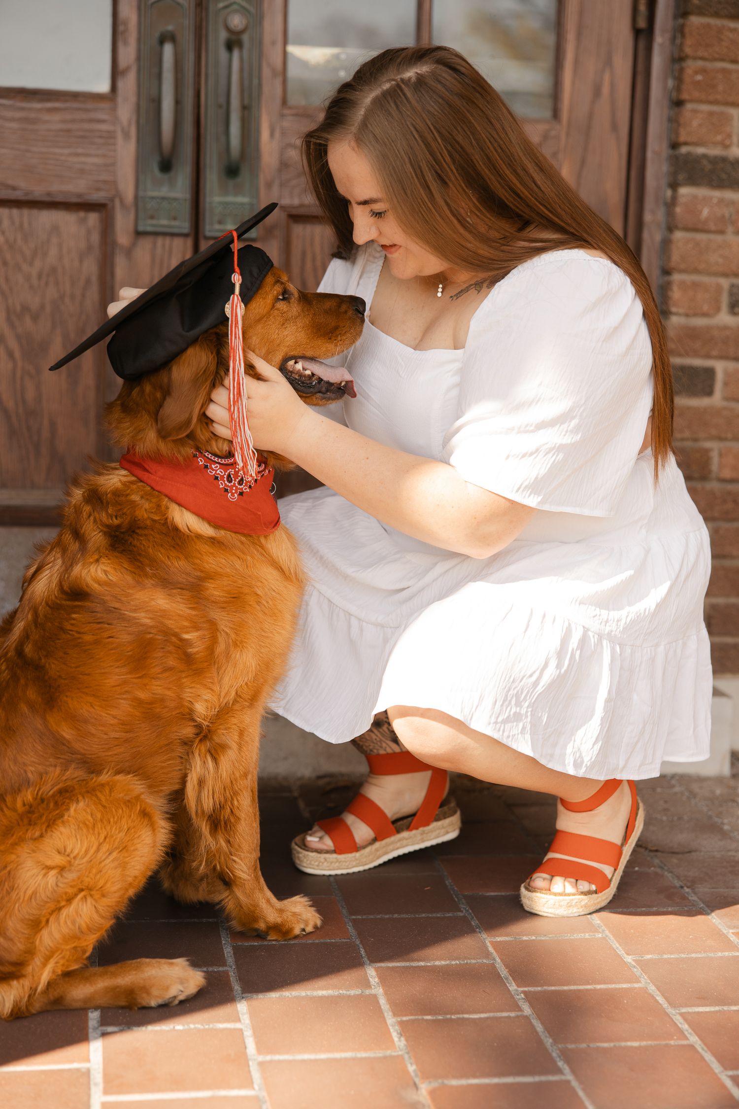 A golden retriever interacts playfully with someone wearing white and orange sandals.