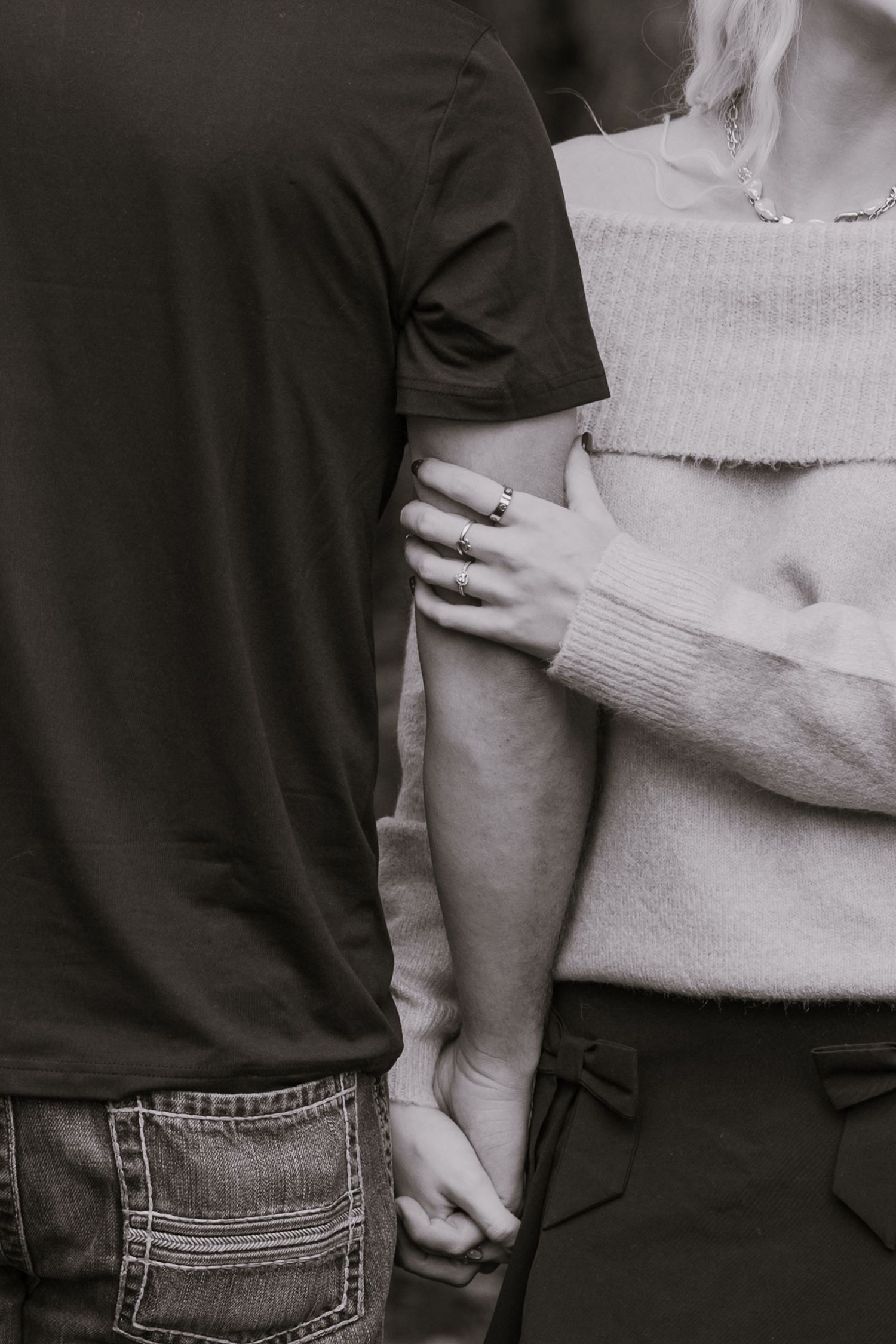 Close-up black and white photo showing couple holding hands and embracing.