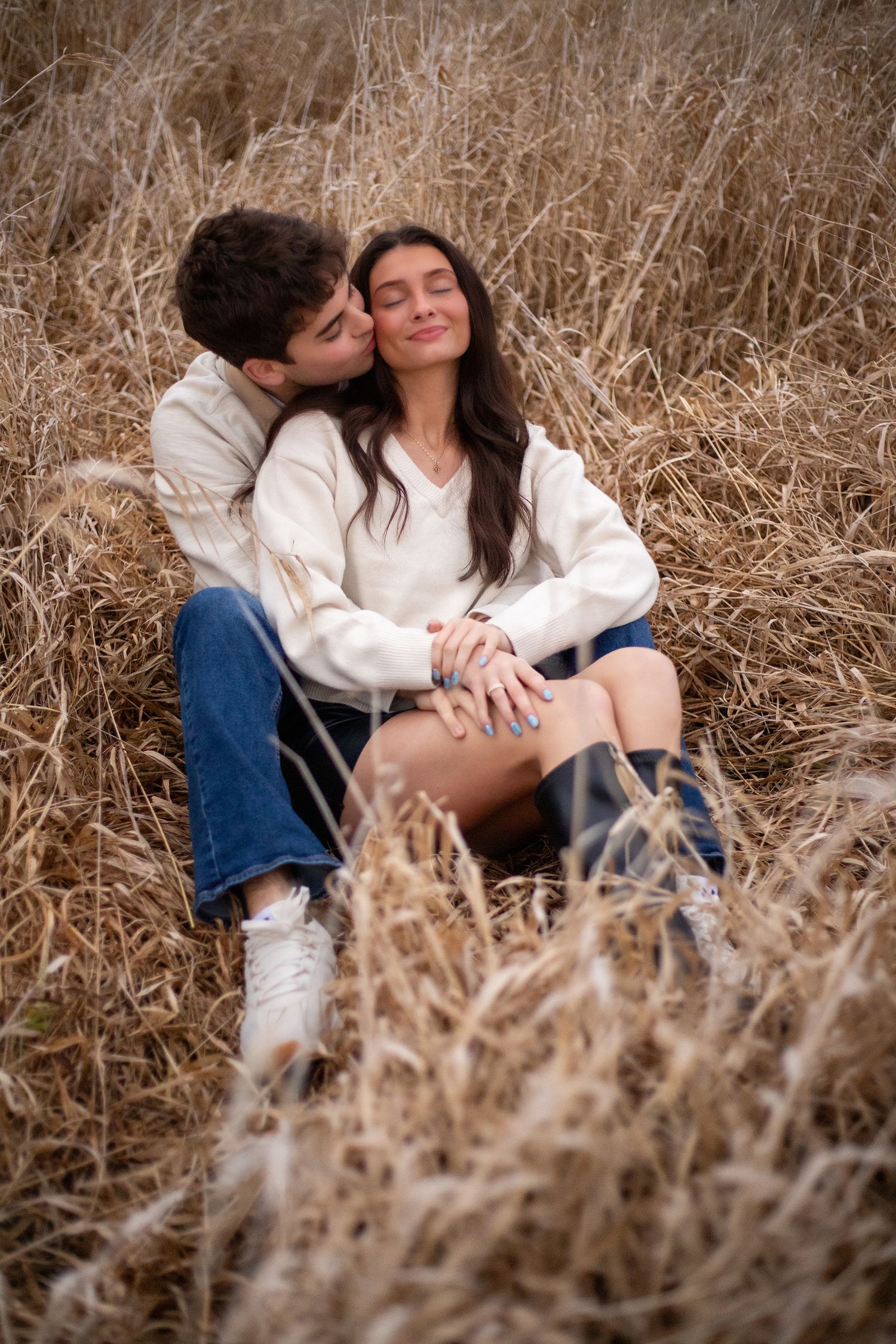 Couple sharing intimate moments among tall dried grass in field.