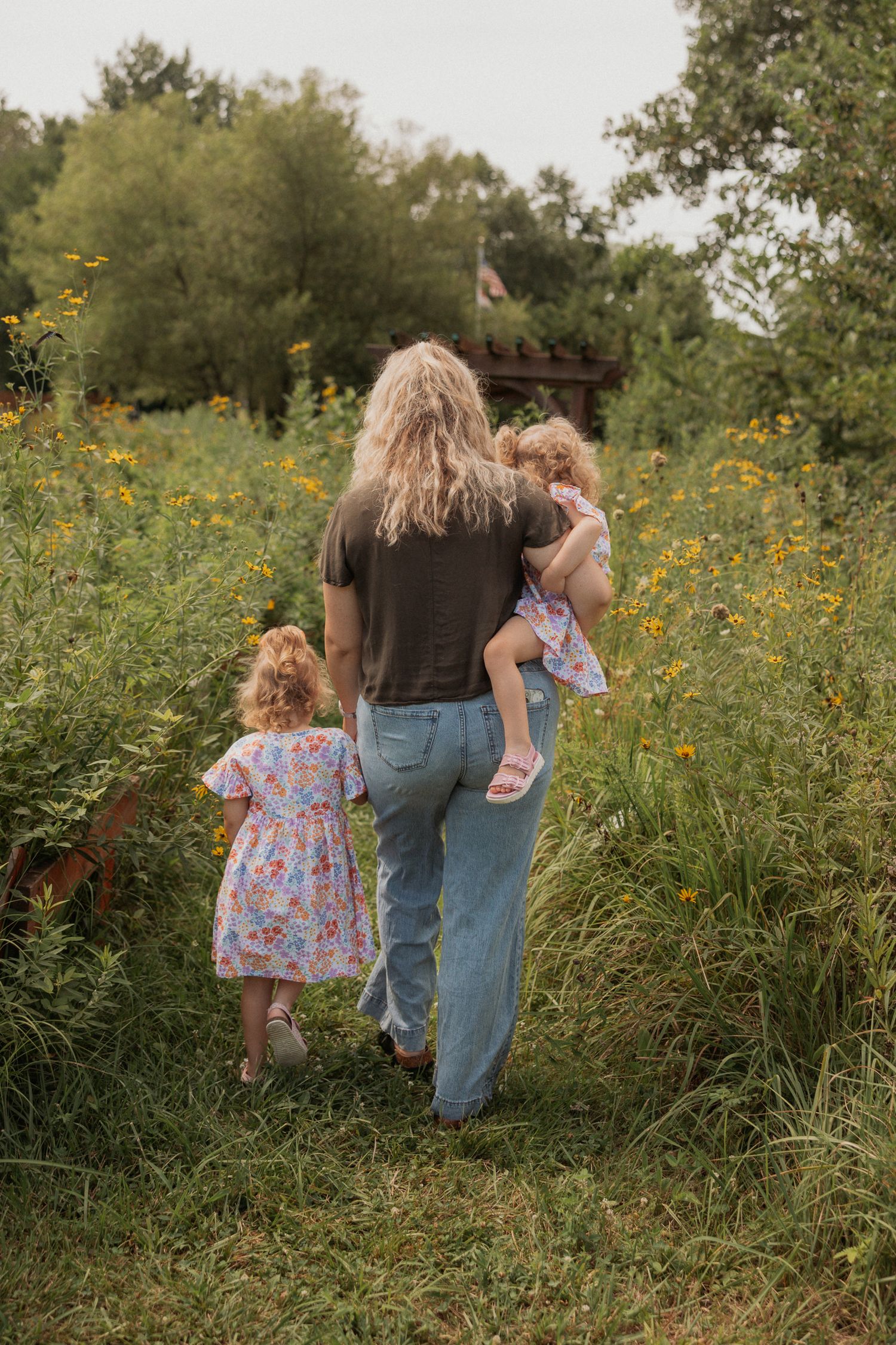 Family walking together through a meadow of yellow wildflowers on a summer day.