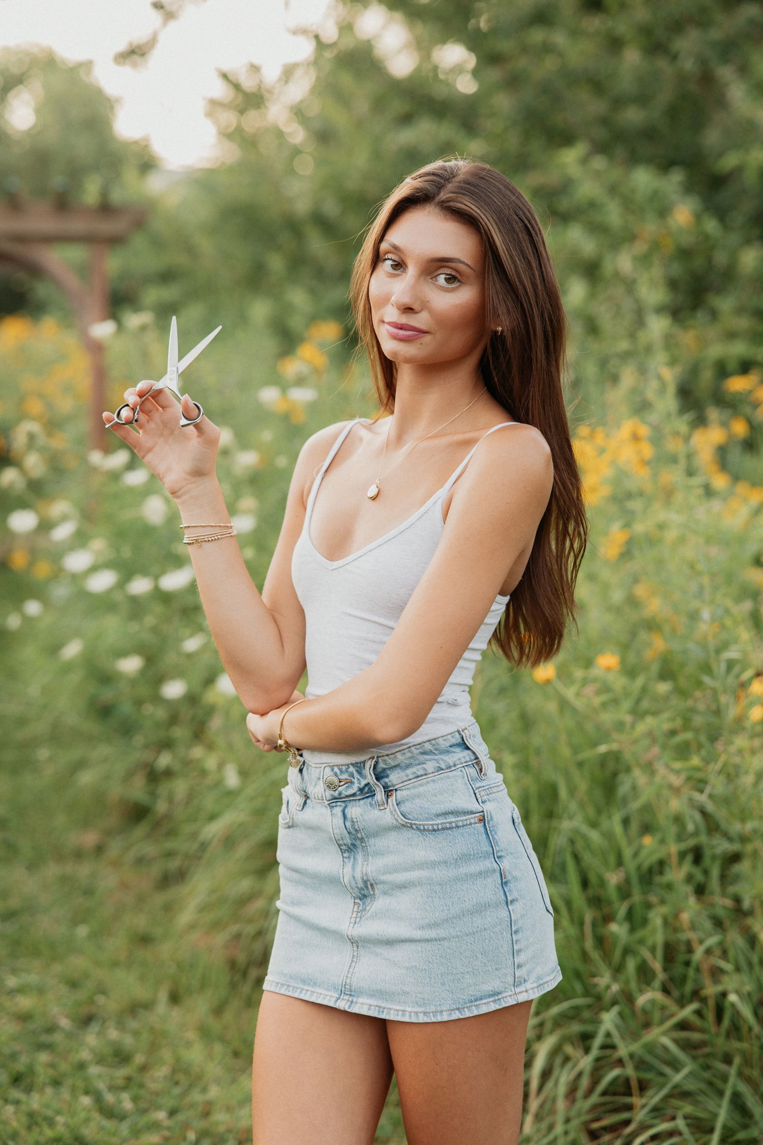 Woman in casual summer outfit poses in a field of wildflowers.