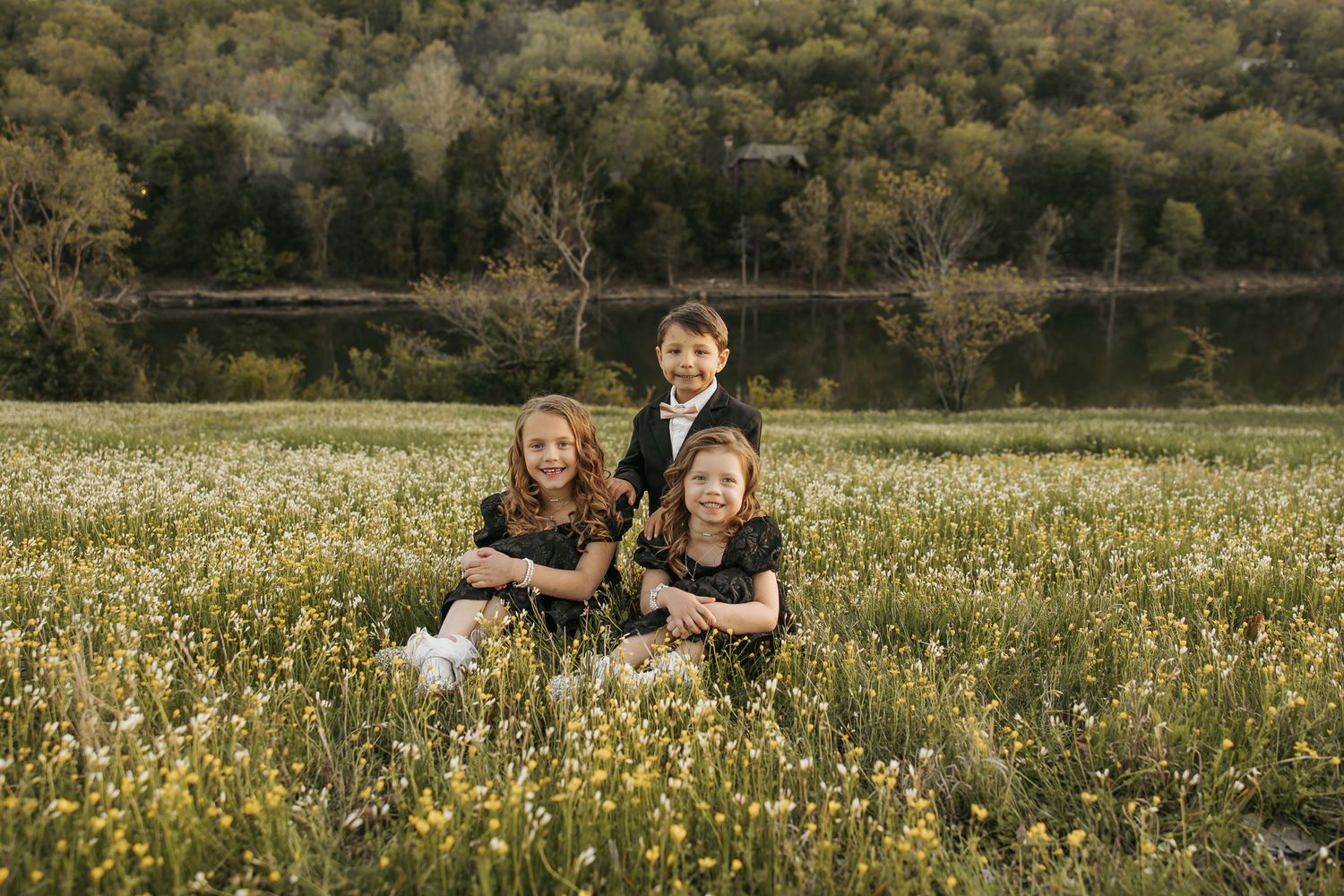 Family enjoying a sunny day together in a wildflower meadow with wooden bench in background.